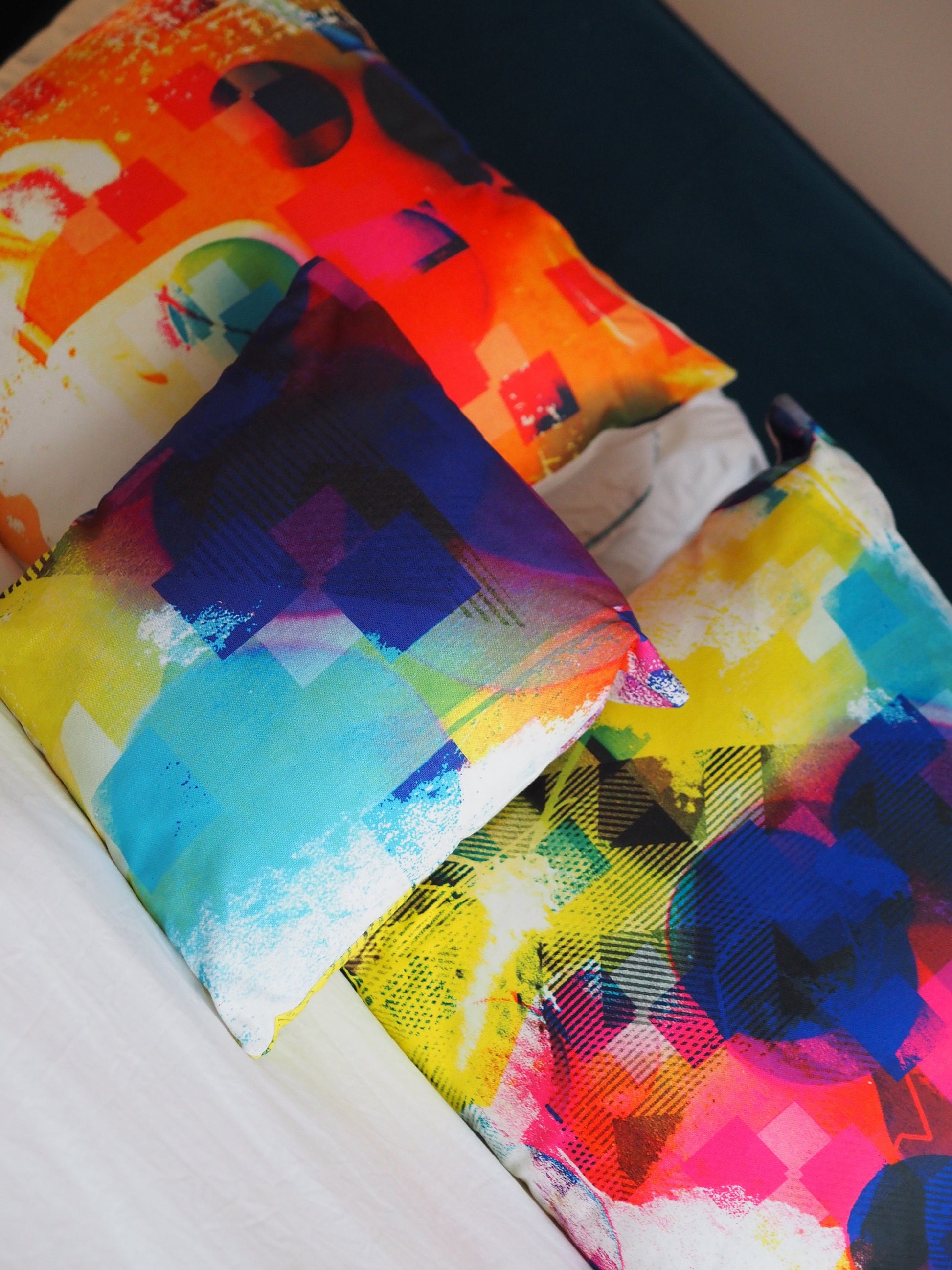 Three Colorful abstract cushions on a bed