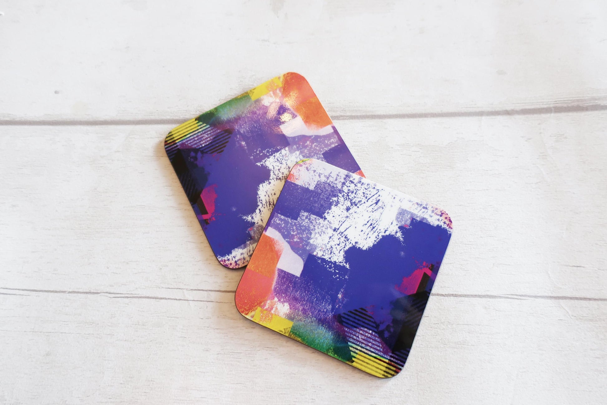 Two colorful coasters on a white wooden surface