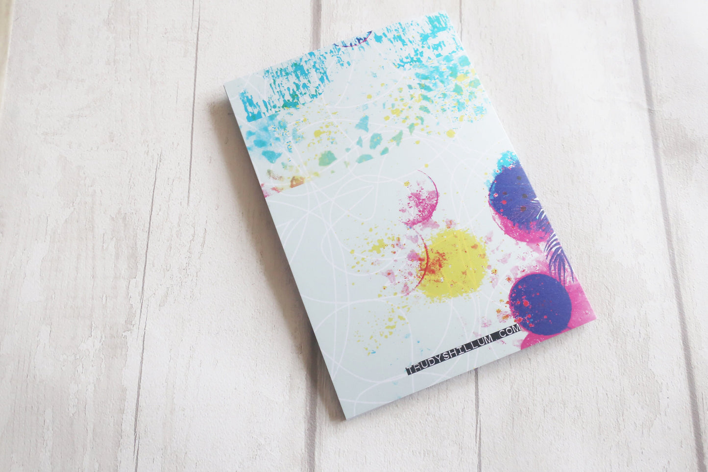 Greetings card with colorful abstract design on a light wooden surface