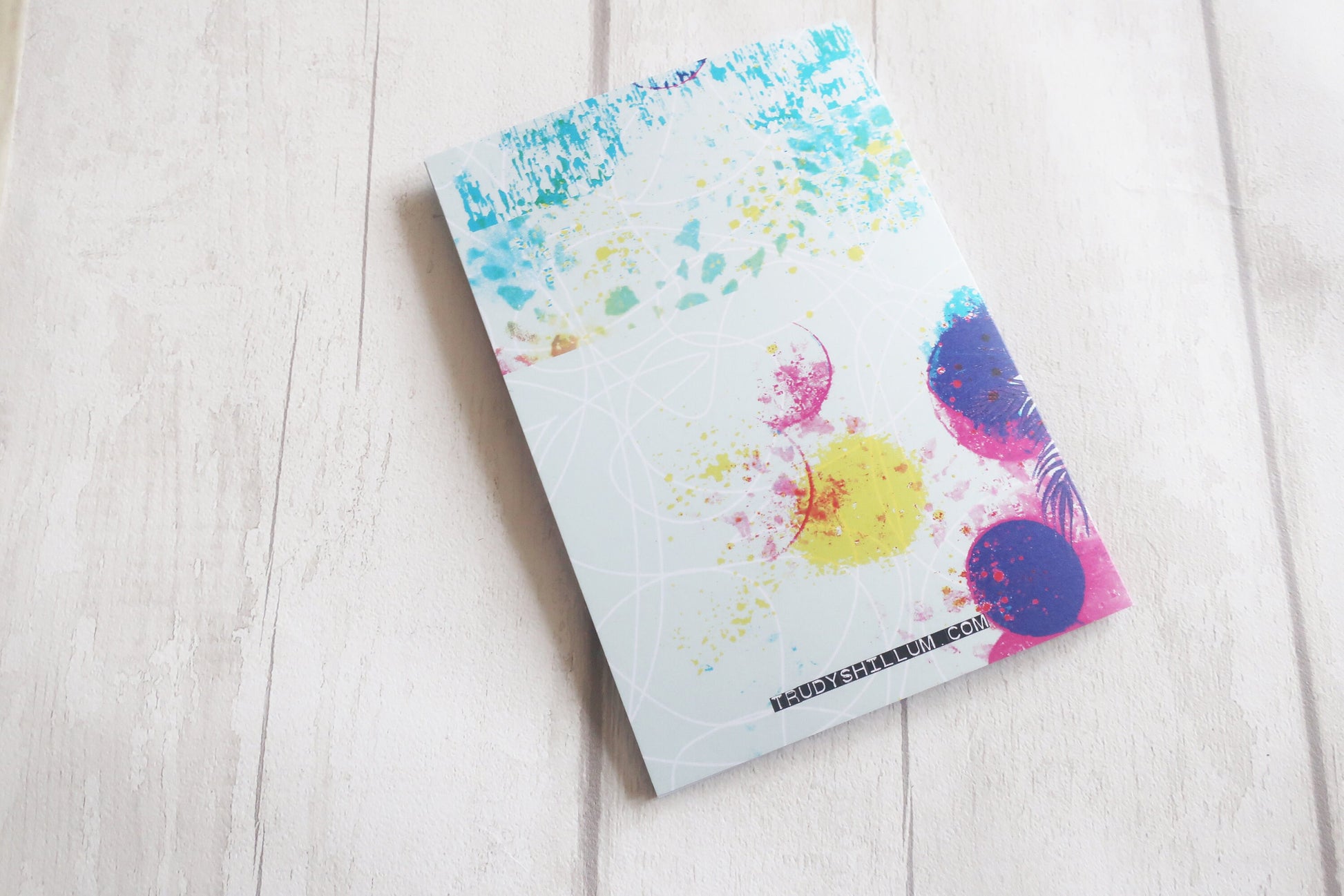 Greetings card with colorful abstract design on a light wooden surface