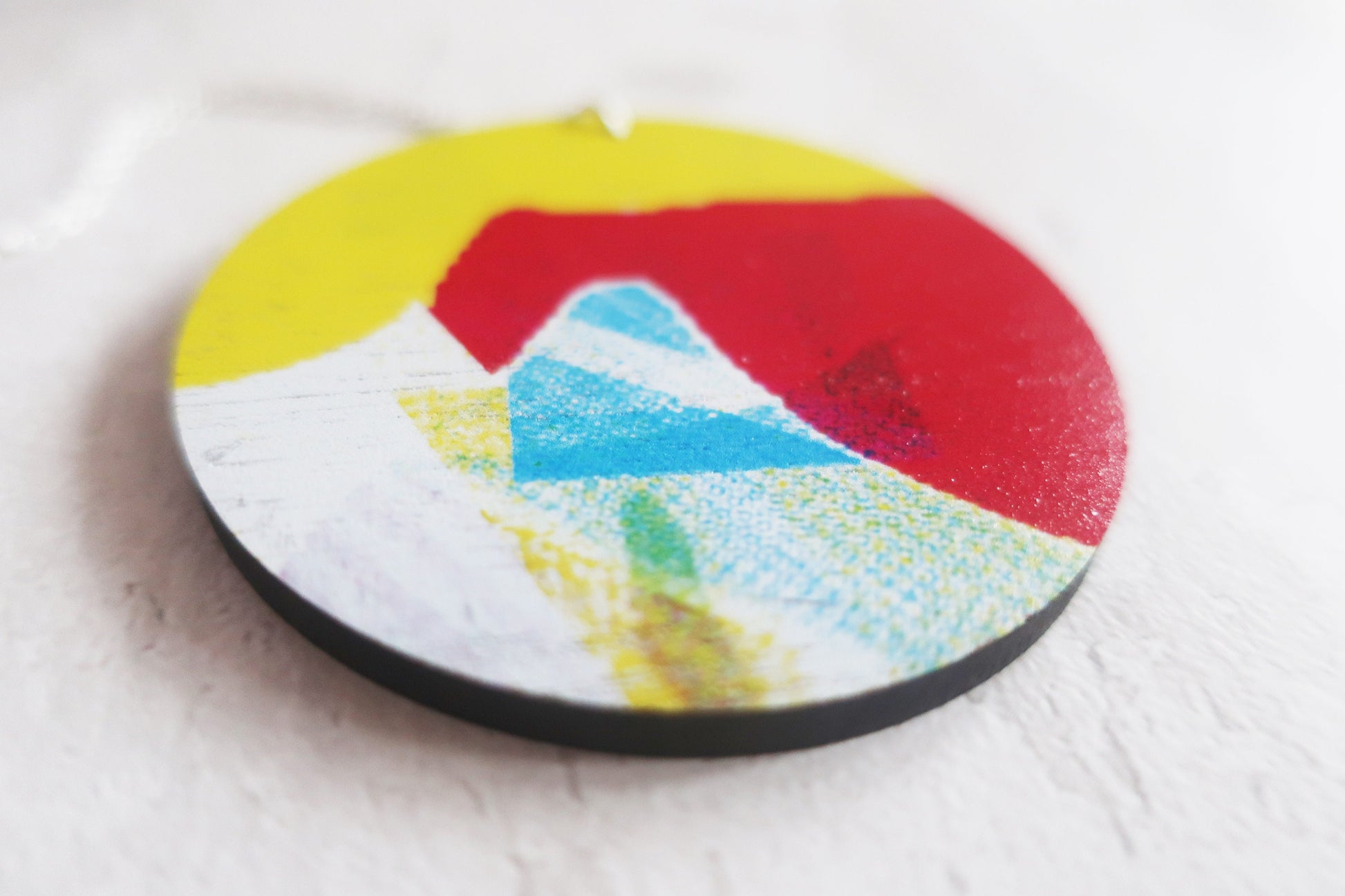 Round pendant with colorful design on a white surface