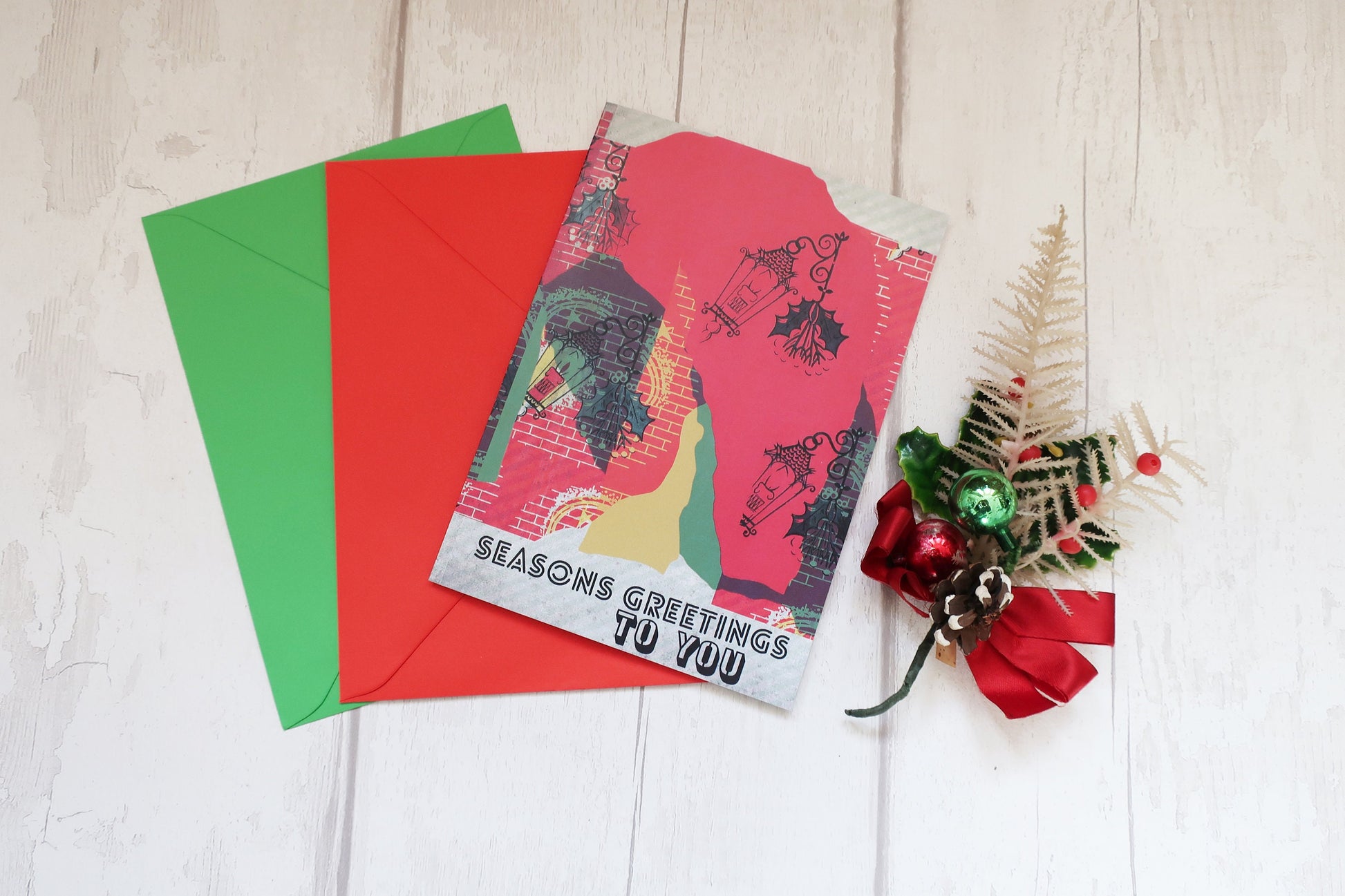 Christmas card with red envelope and decorative elements on a light wooden surface