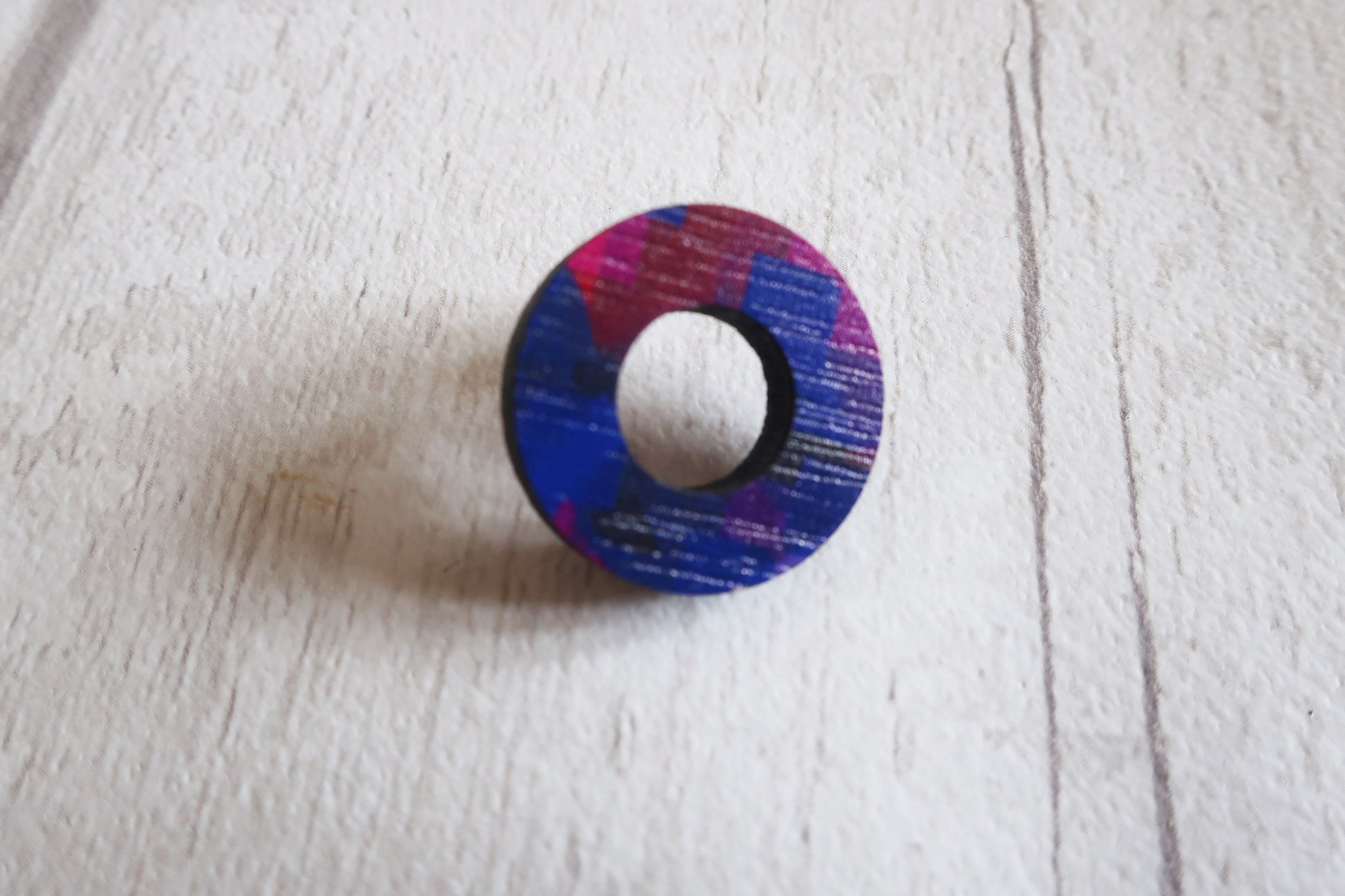 Colorful circular earring on a light wooden surface