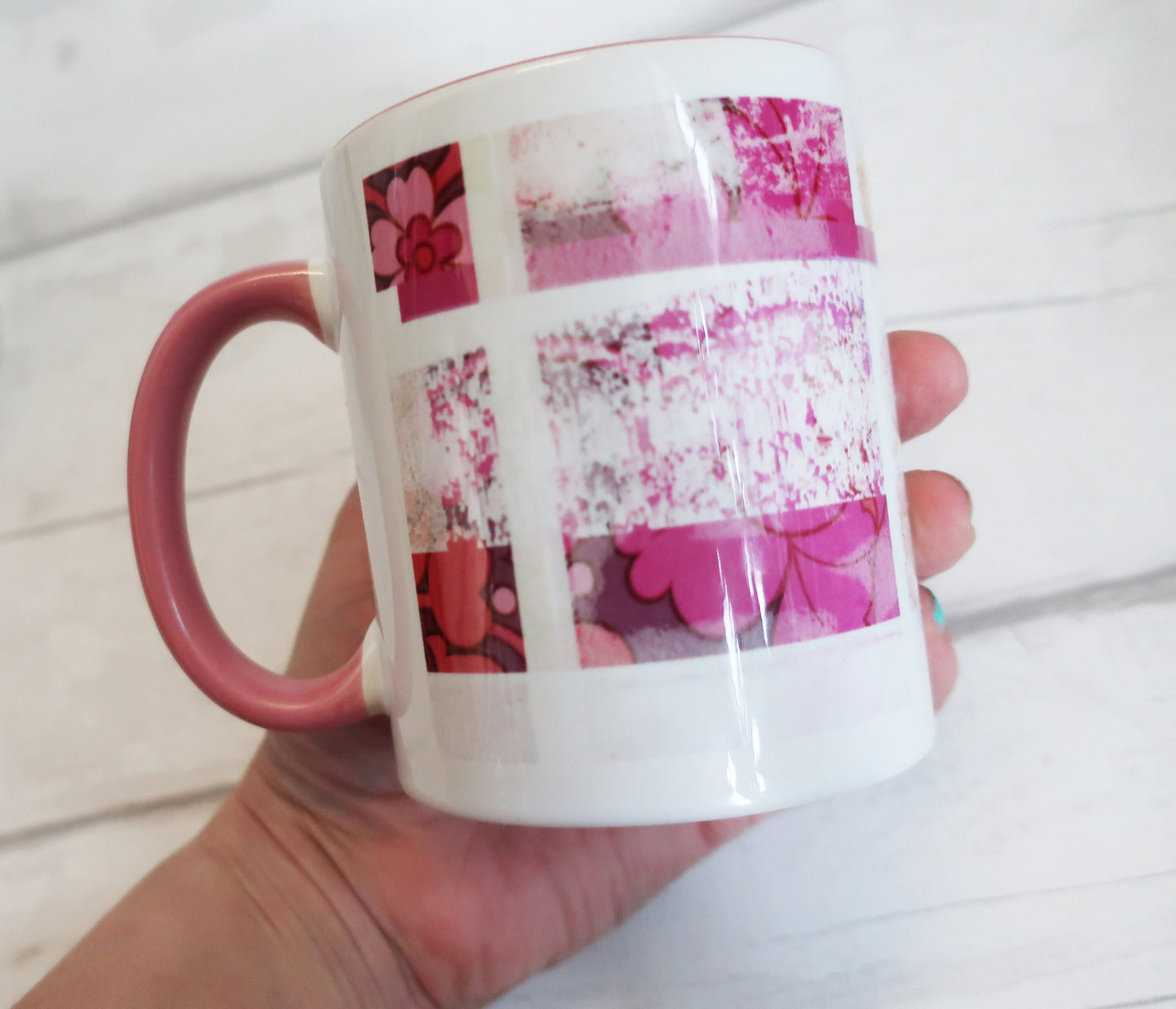 Mug with pink floral design held by a hand on a light wooden surface