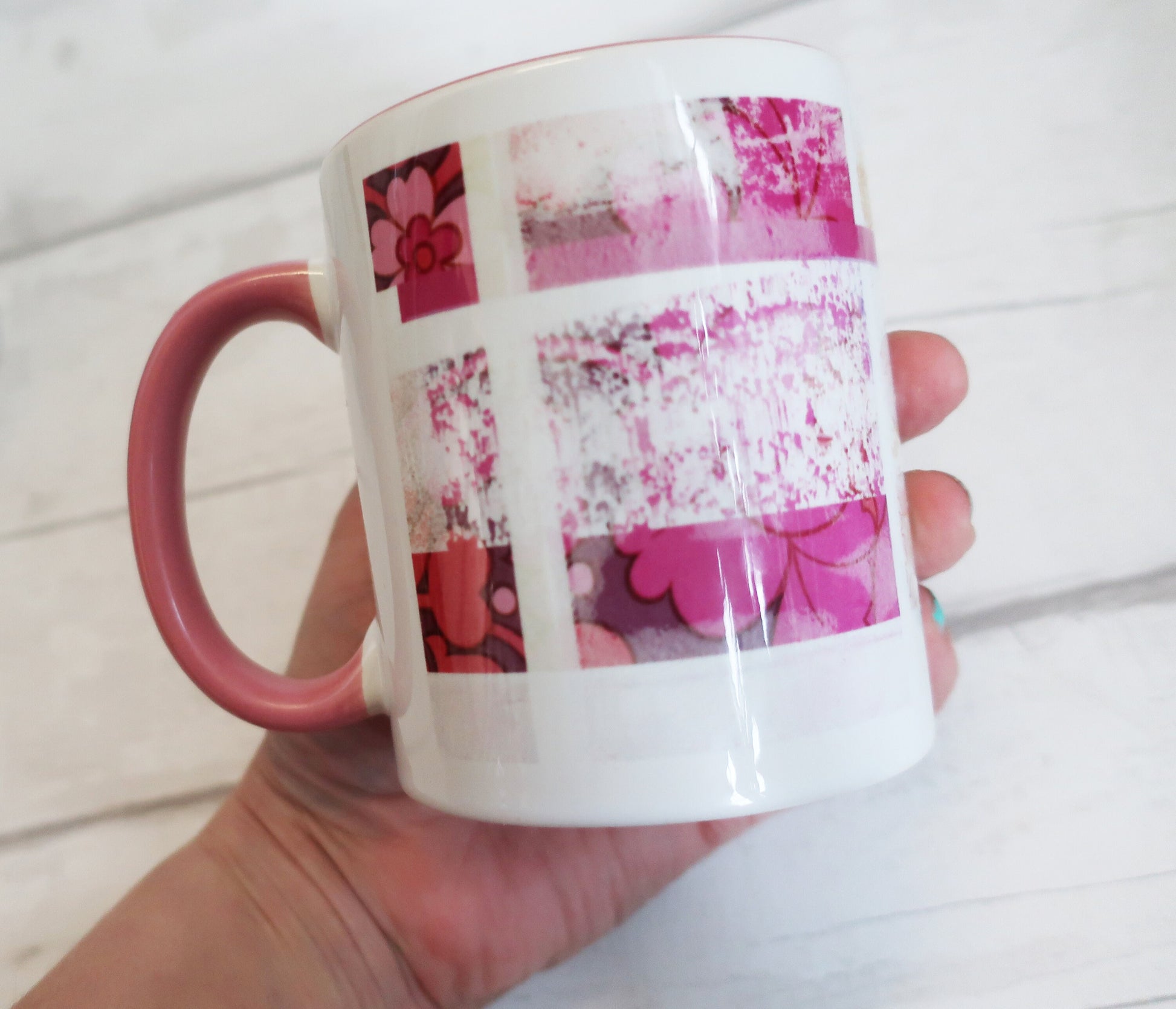 Mug with pink floral design held by a hand on a light wooden surface