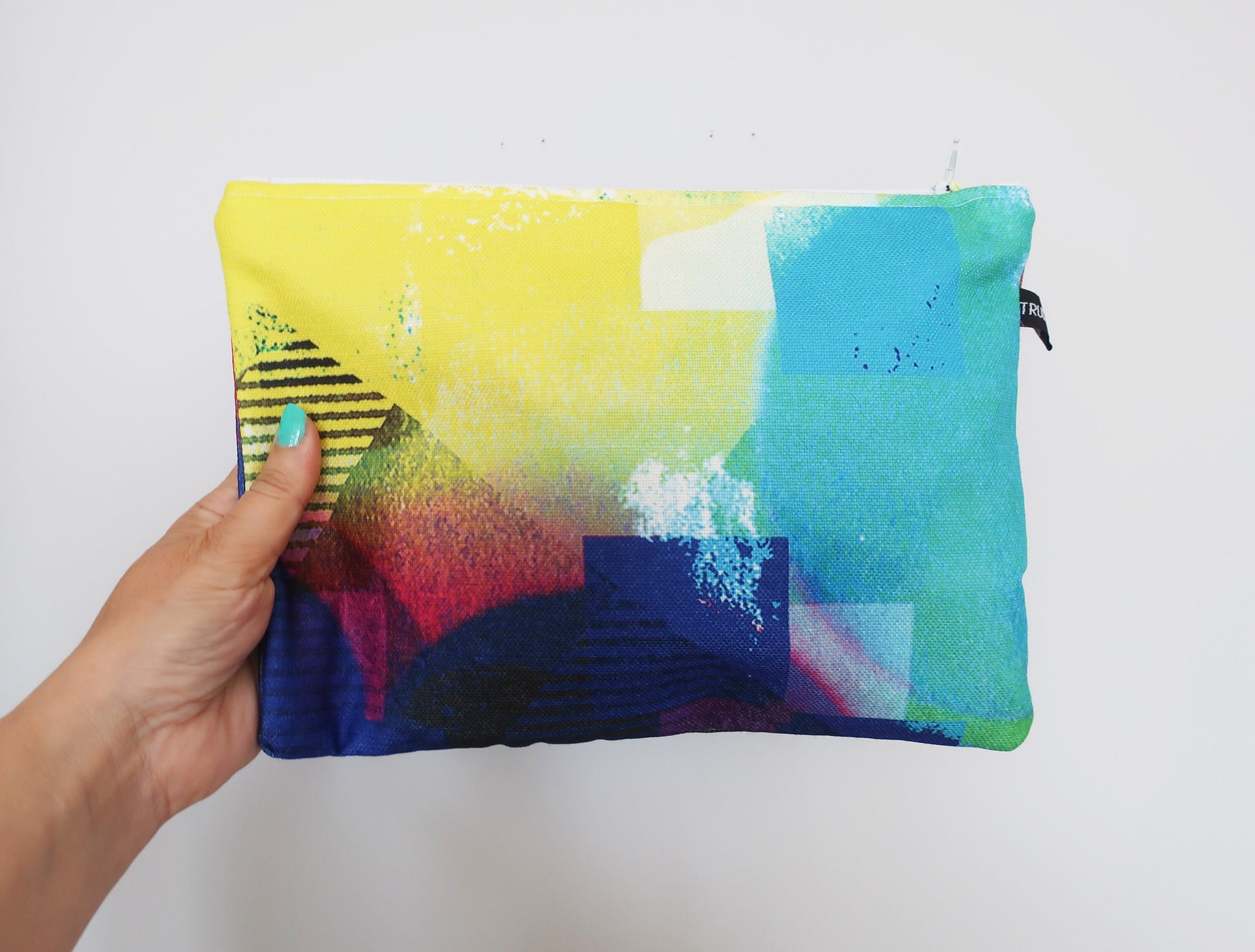 Colorful pouch held by a hand against a white background