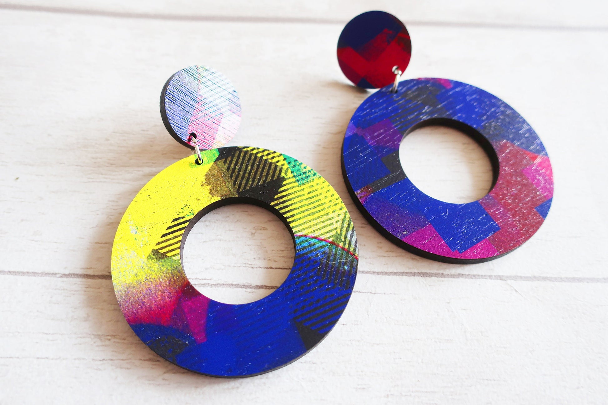 Colorful round earrings on a light wooden surface