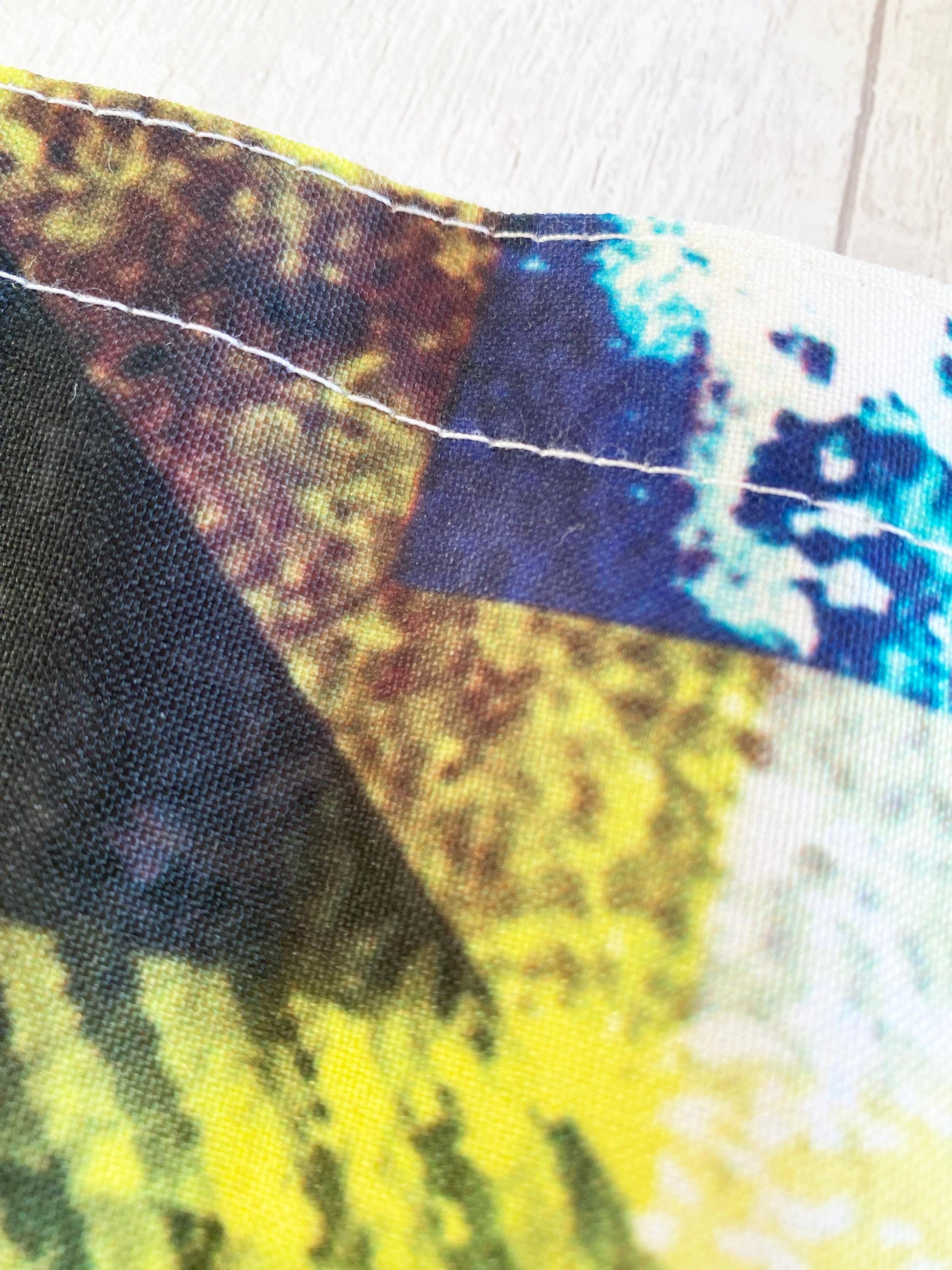 Close-up of a colorful fabric with a pattern of blue, yellow, and white on a wooden surface.
