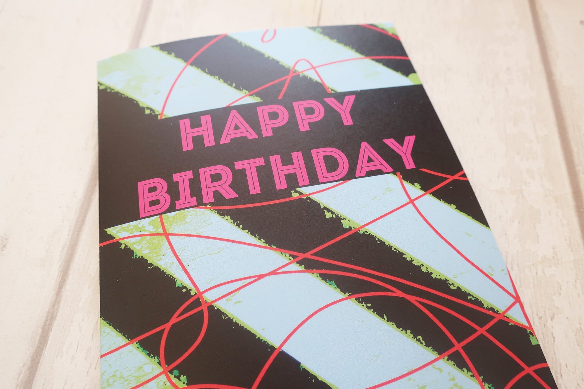 Birthday card with geometric design and 'Happy Birthday' text on a light wooden surface
