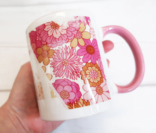 Floral-patterned mug held by a hand on a white background