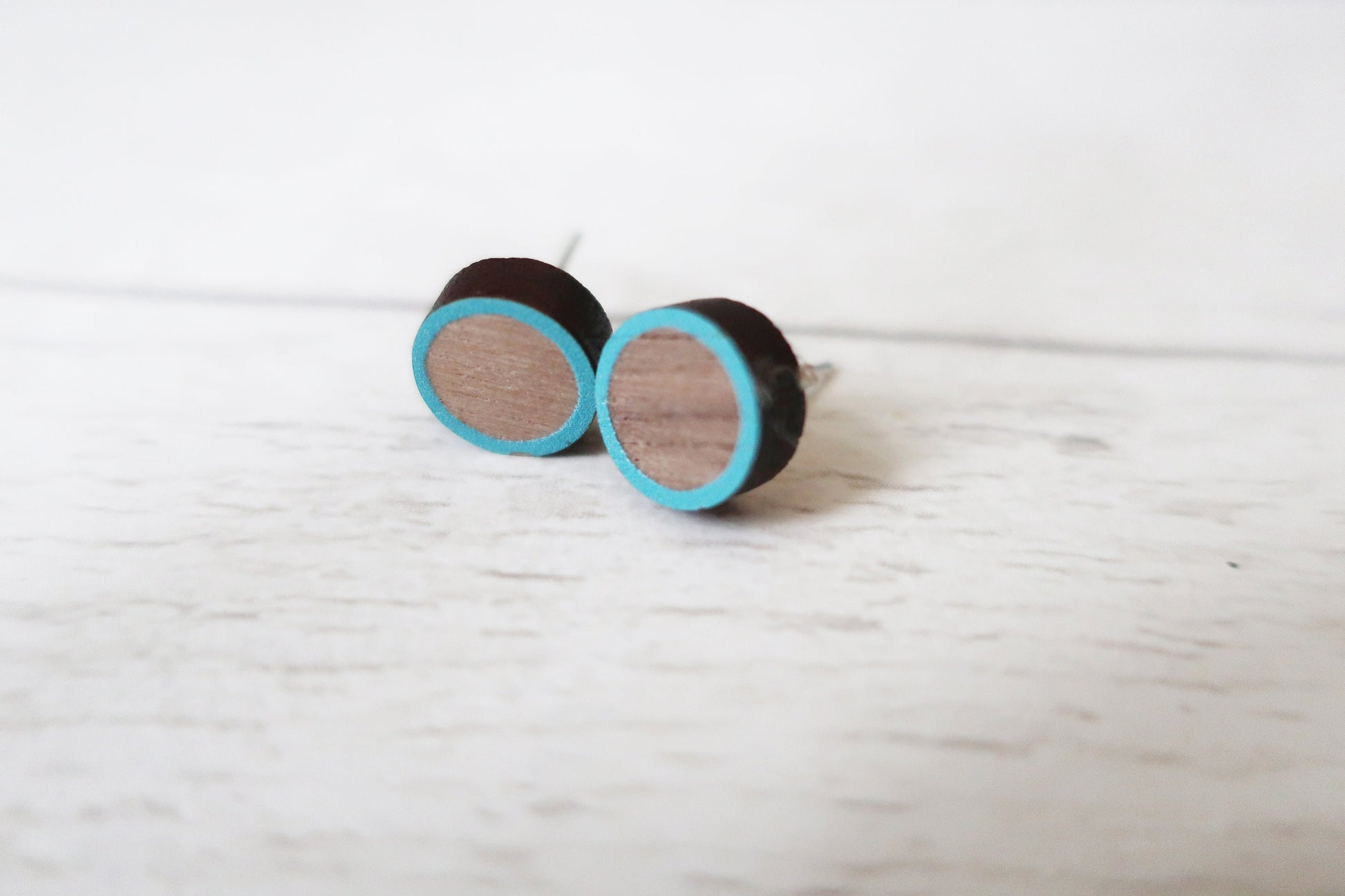 Round earrings with black and blue circular design on a light wooden surface