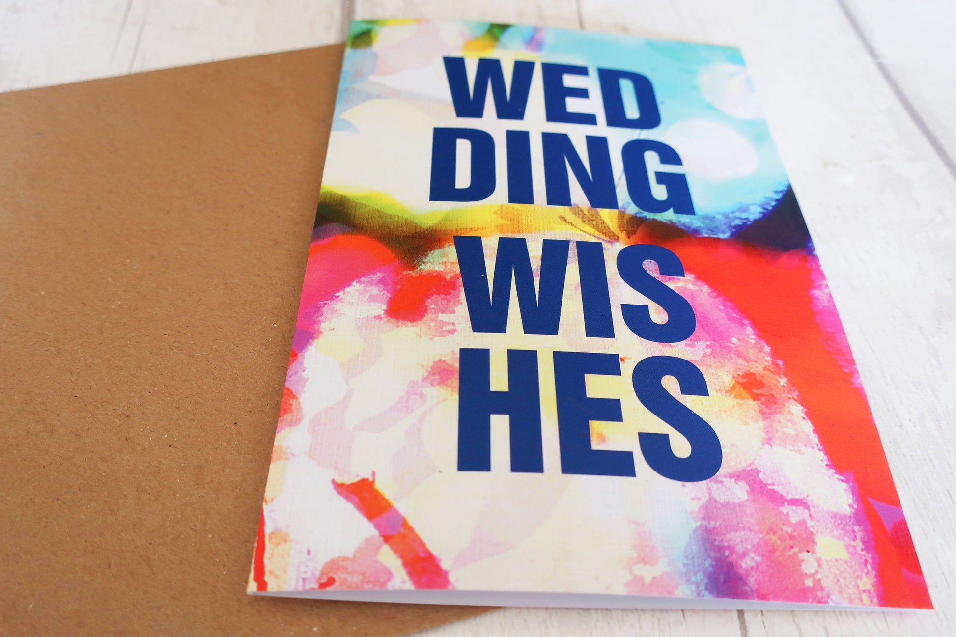 Colorful card with 'Wedding Wishes' text on a white surface