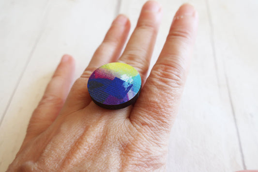 Hand wearing a colorful ring on a light background