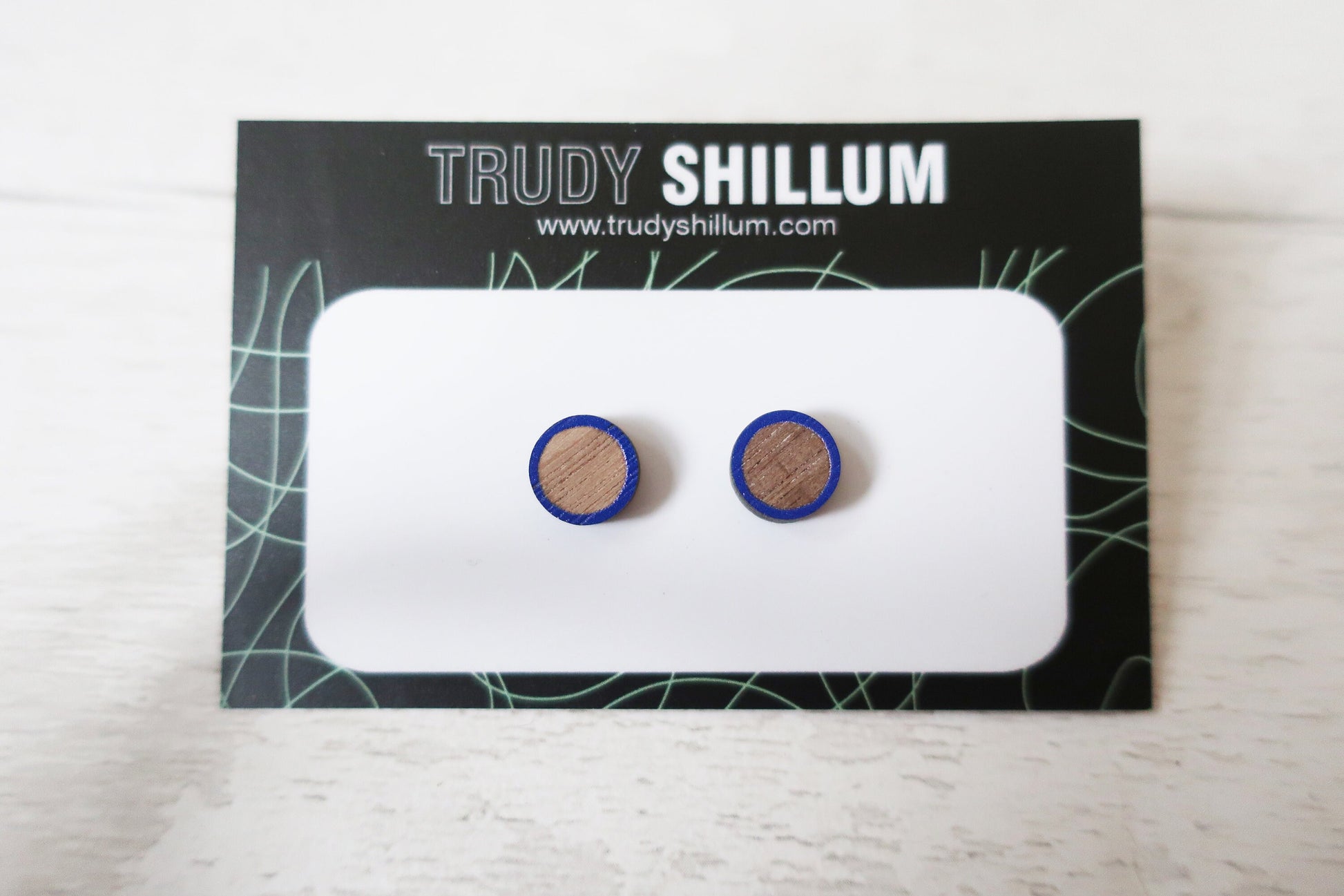 Wooden earrings with blue accents on a Trudy Shillum branded card.