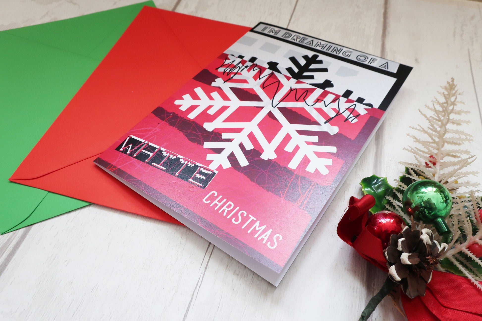 Christmas card with snowflake design and red envelope on a light surface.