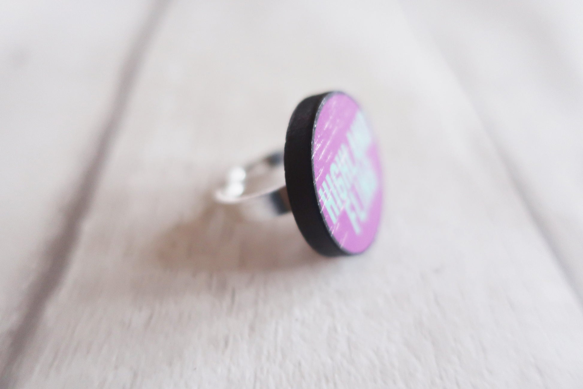 Ring with a pink and black circular design on a light fabric background