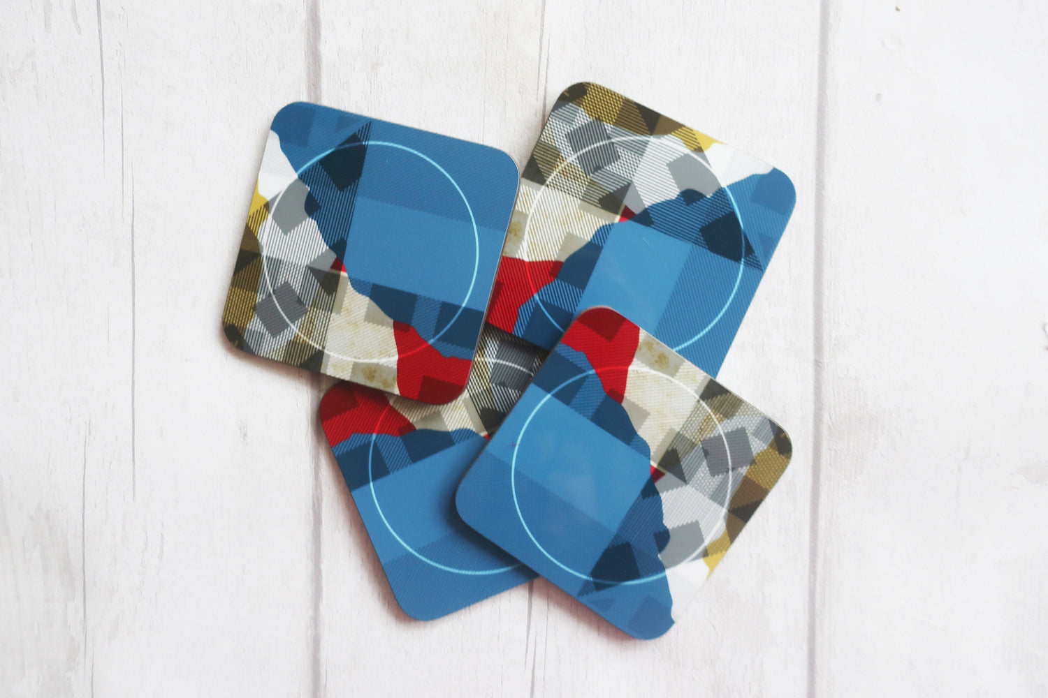 Set of geometric patterned coasters on a white wooden surface