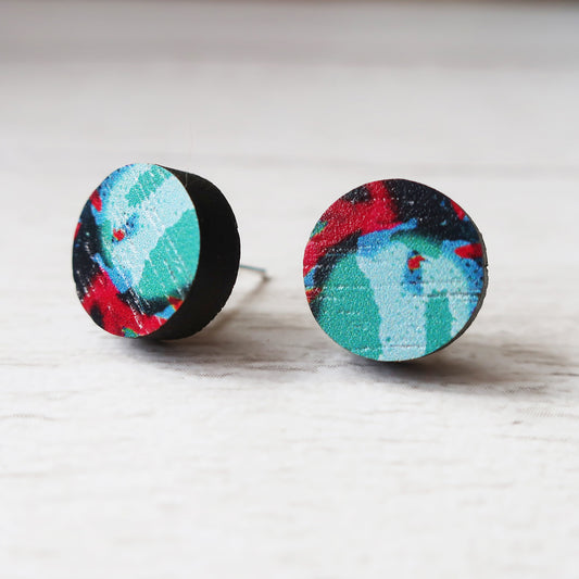 Pair of round earrings with colorful design on a light wooden surface