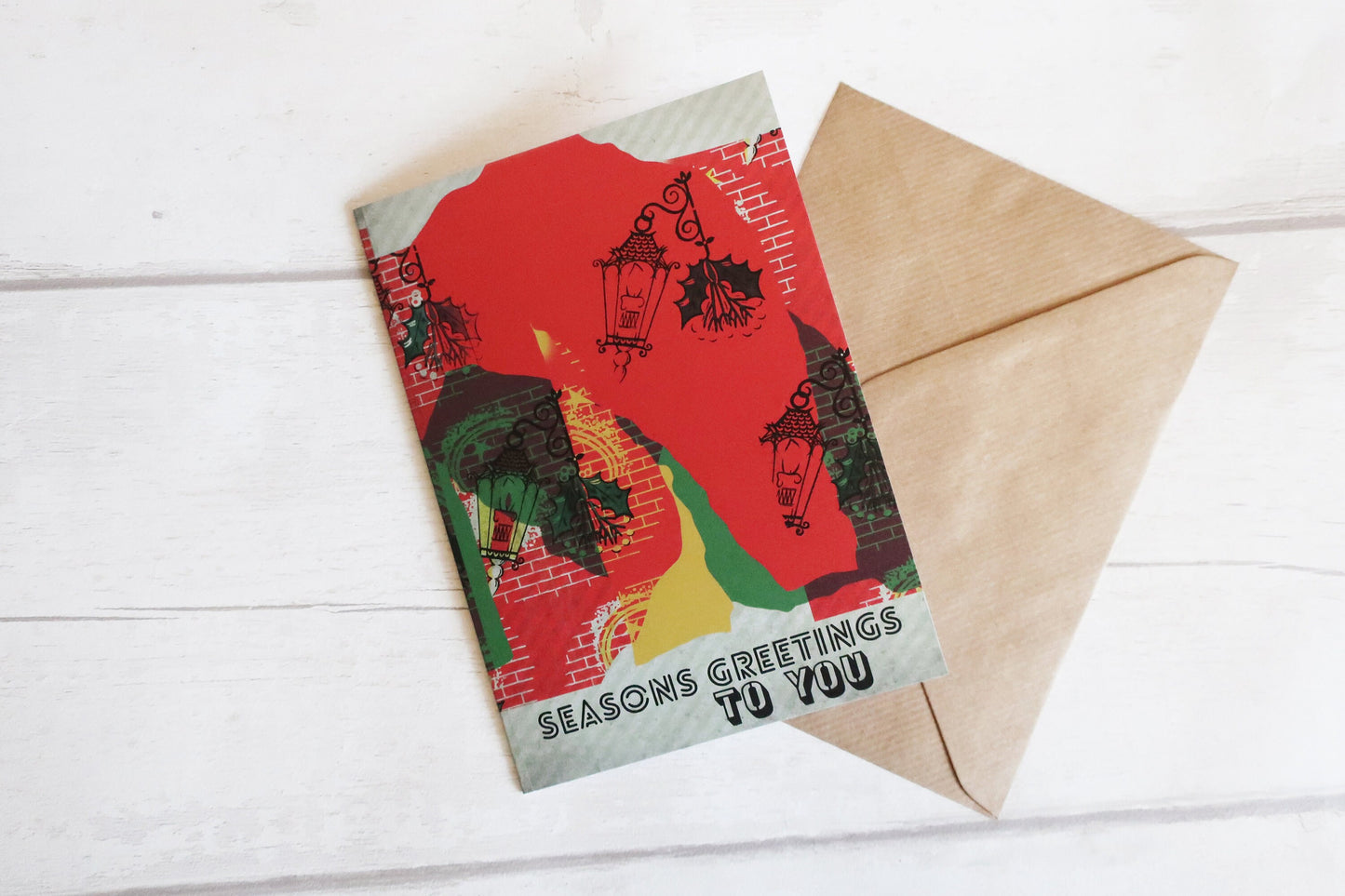 Greeting card with festive design and envelope on a white wooden surface