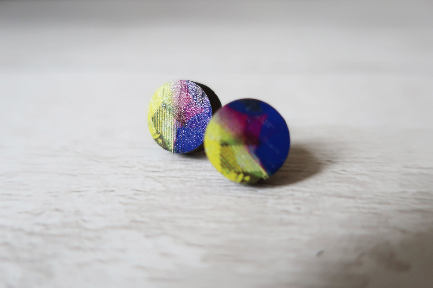 Pair of colorful round earrings on a light wooden surface