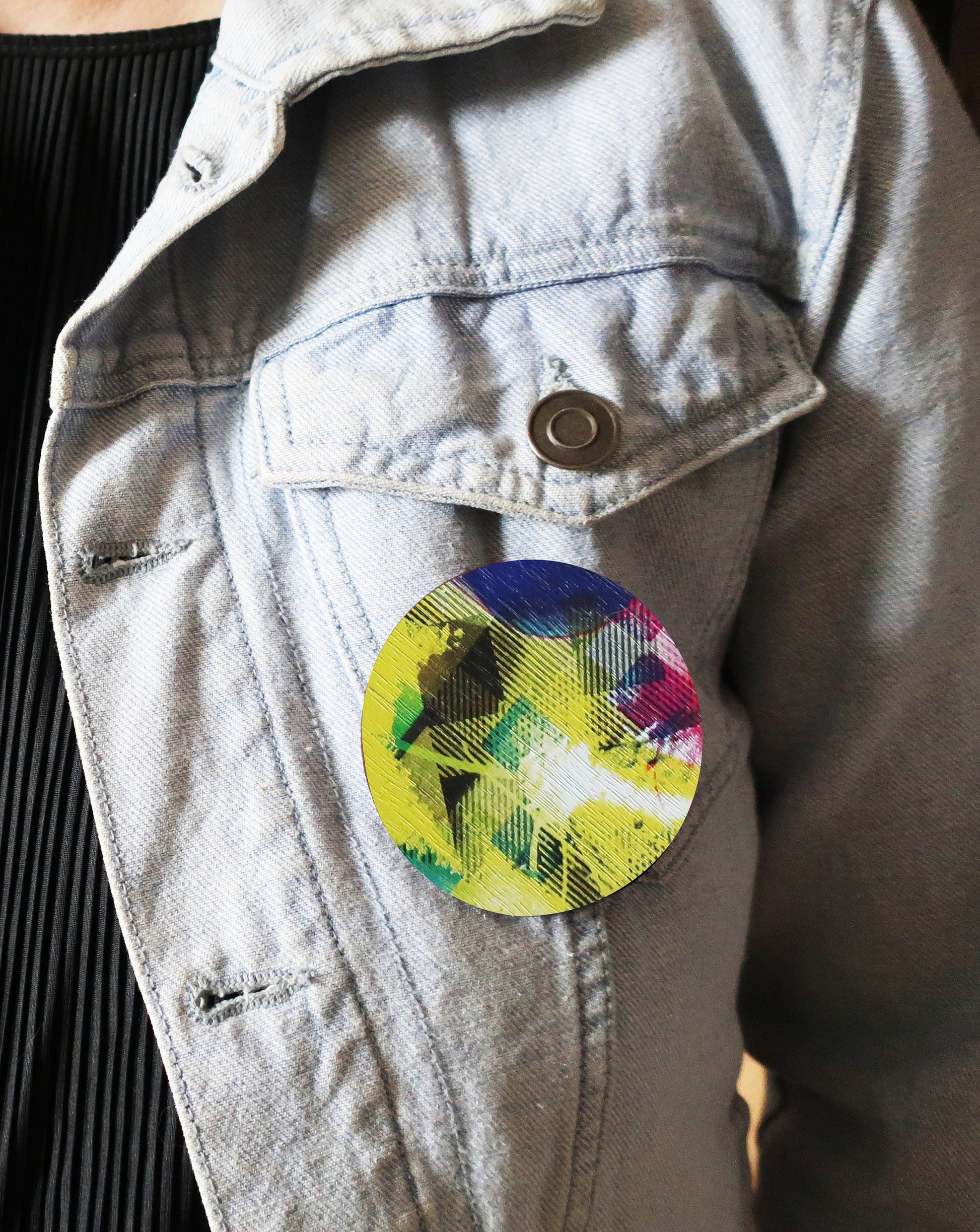 Colorful round brooch on a light blue denim jacket