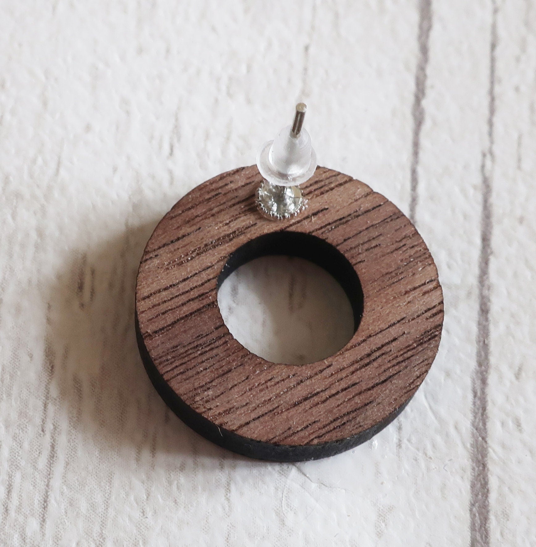 Wooden circular earring back on a textured white background