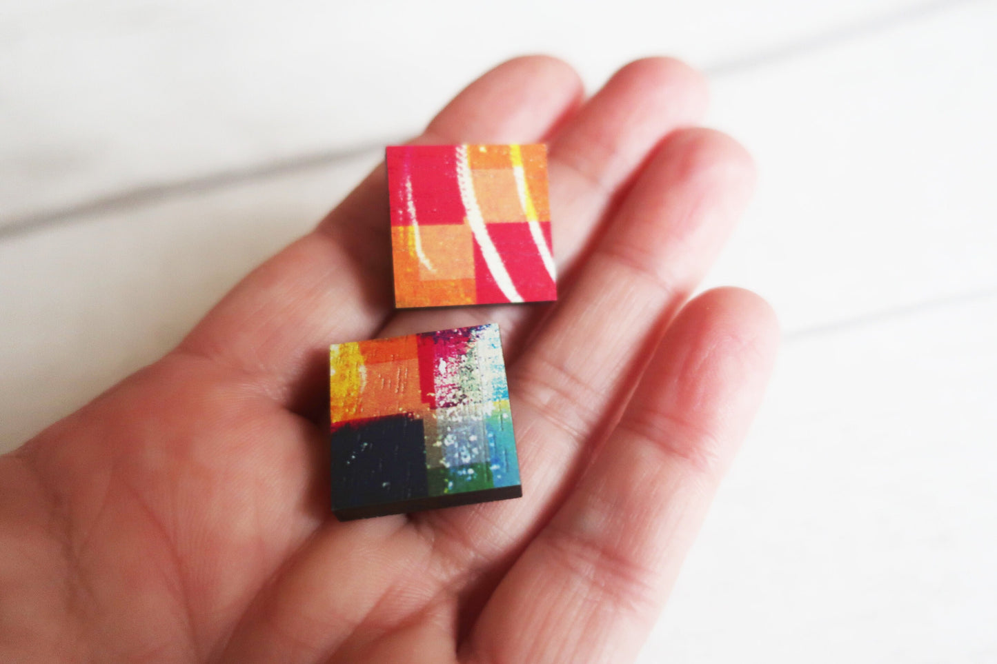 Colorful earrings  held in a hand against a white background