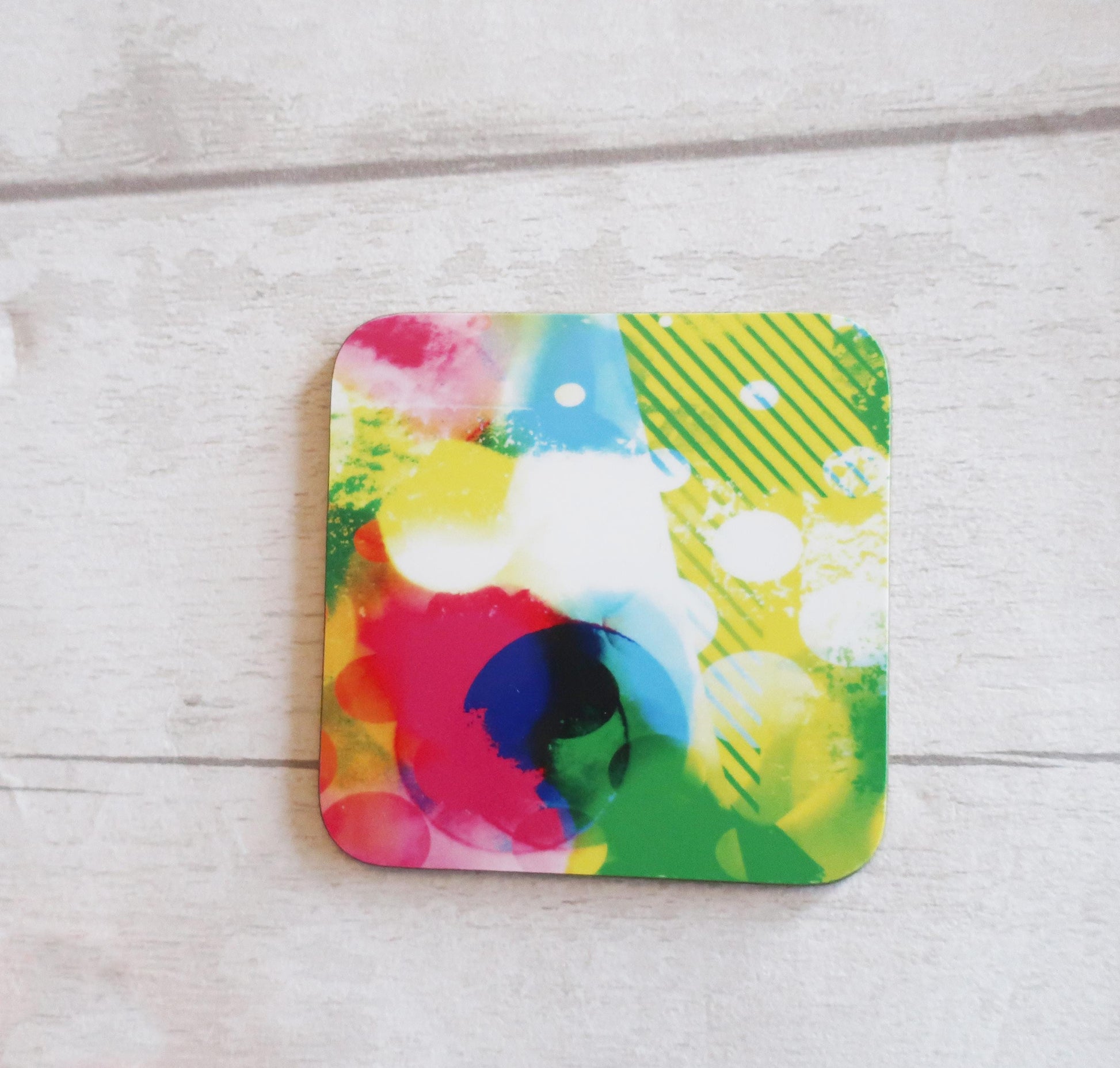 Colorful abstract design coaster on a light wooden surface