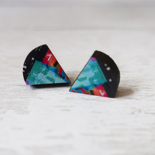 Triangular earrings with colorful patterns on a light wooden surface