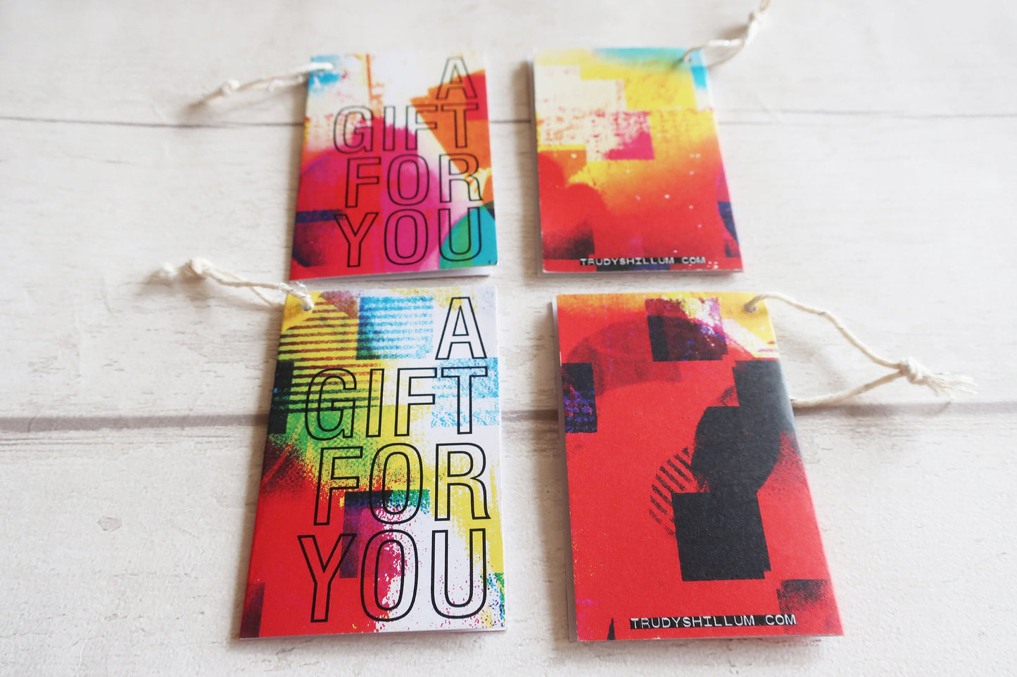 Four colorful gift tags on a white wooden surface