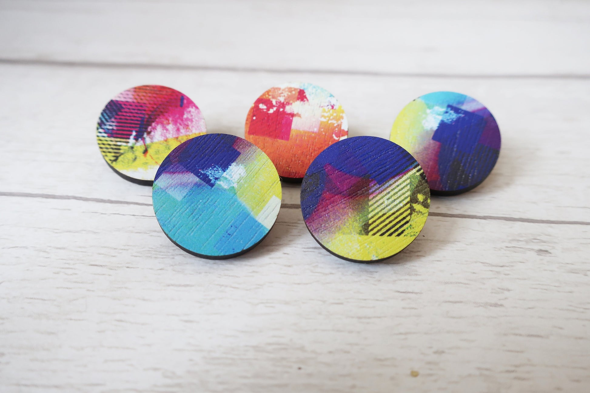 Set of colorful round pin badges on a light wooden surface
