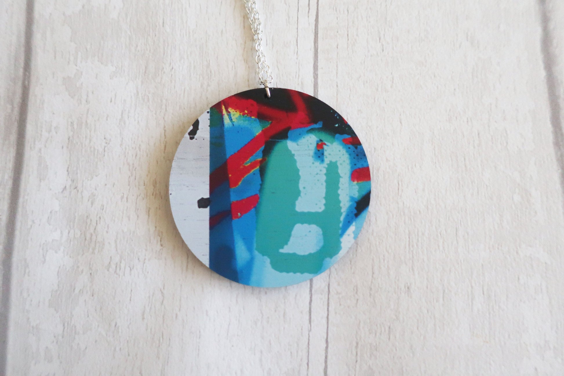 Round colorful pendant on a chain against a light wooden background