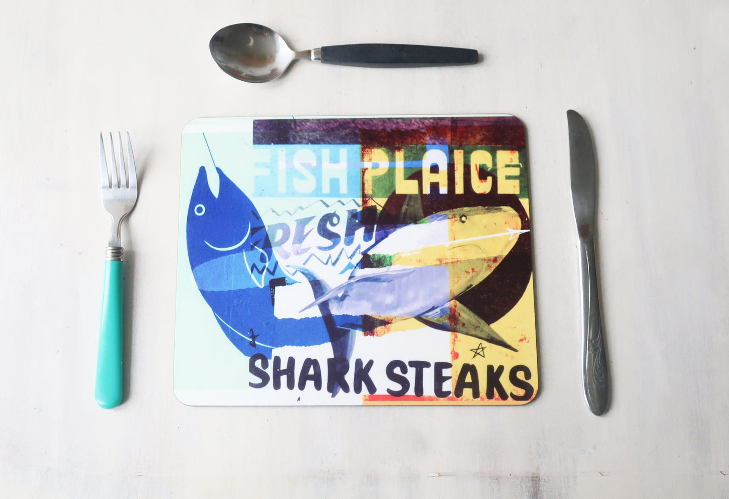 Colorful placemat with fish design and text on a white surface with cutlery.