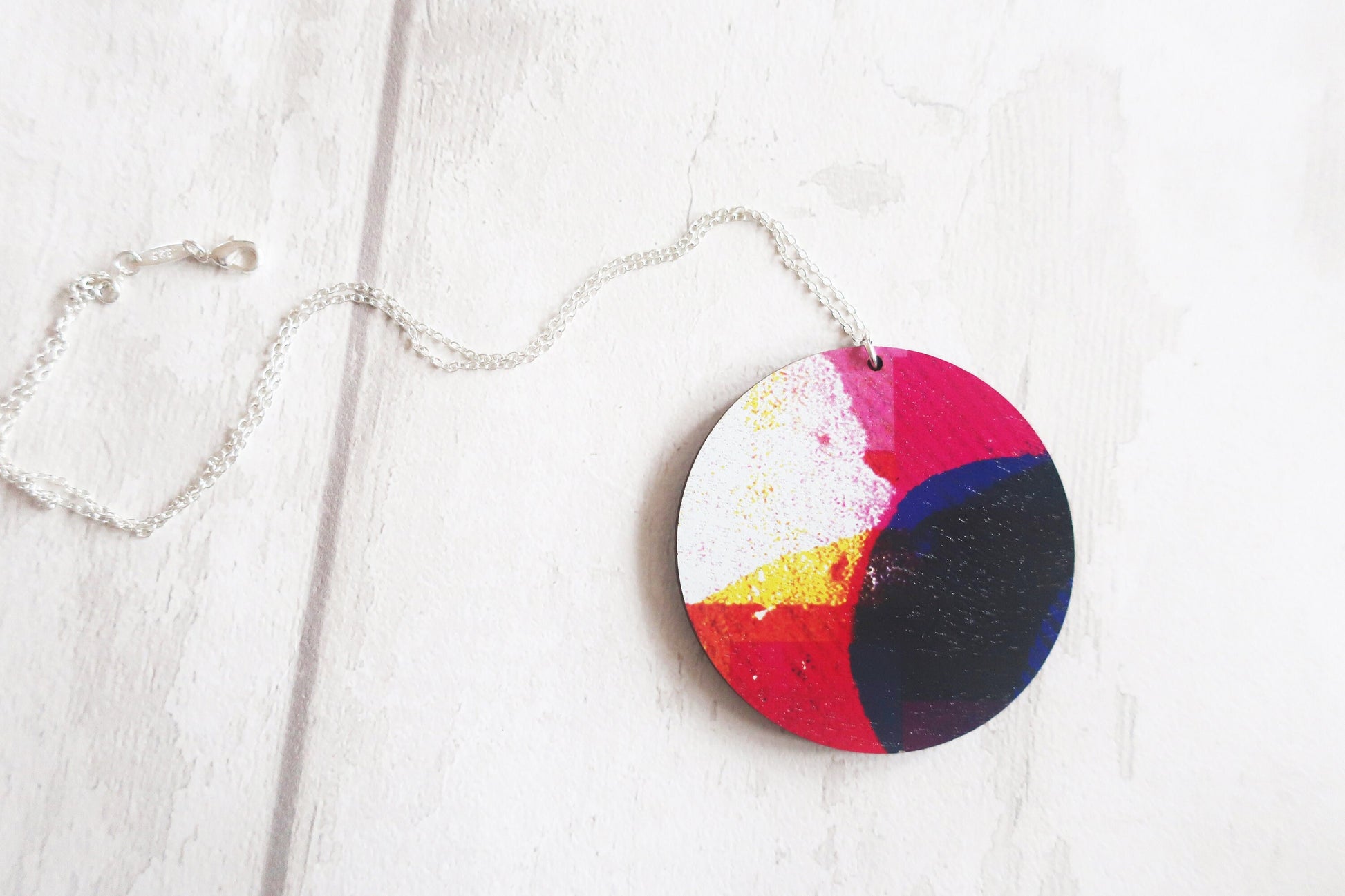Colorful circular pendant on a chain against a white background