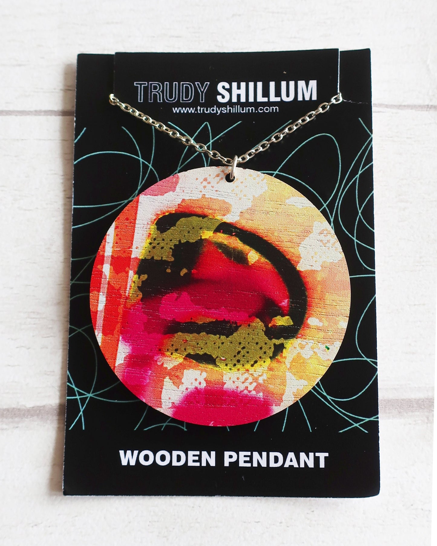 Wooden pendant on a Trudy Shillum branded card with a colorful design.