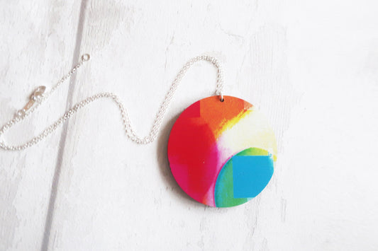 Colorful circular pendant on a chain against a white background