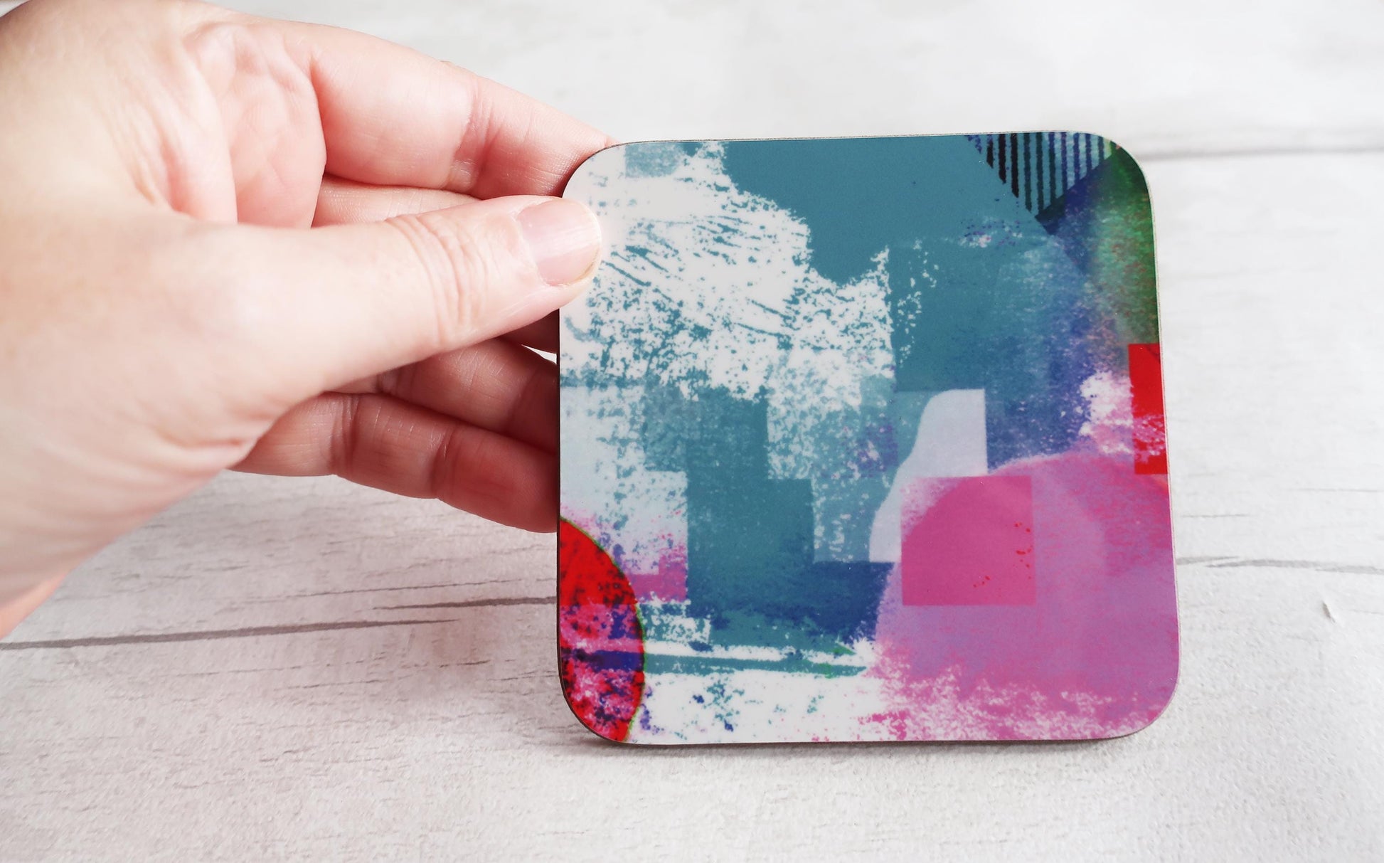 Coaster with abstract design held by a hand on a light wooden surface
