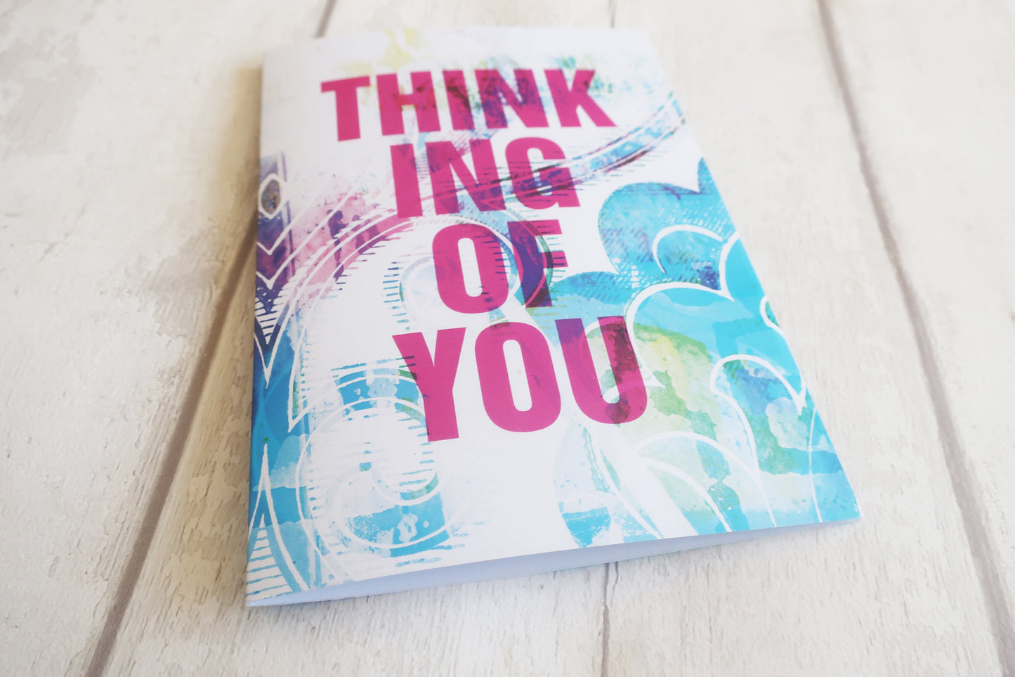 Greeting card with 'Think of You' text on a light wooden surface