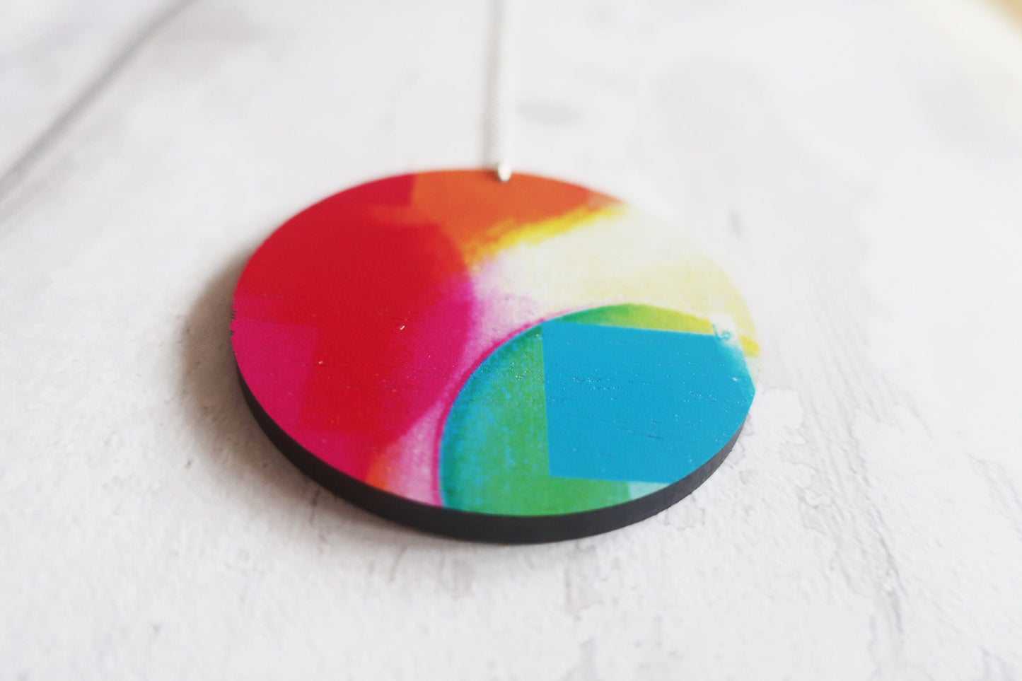 Colorful circular pendant with a rainbow pattern on a white background