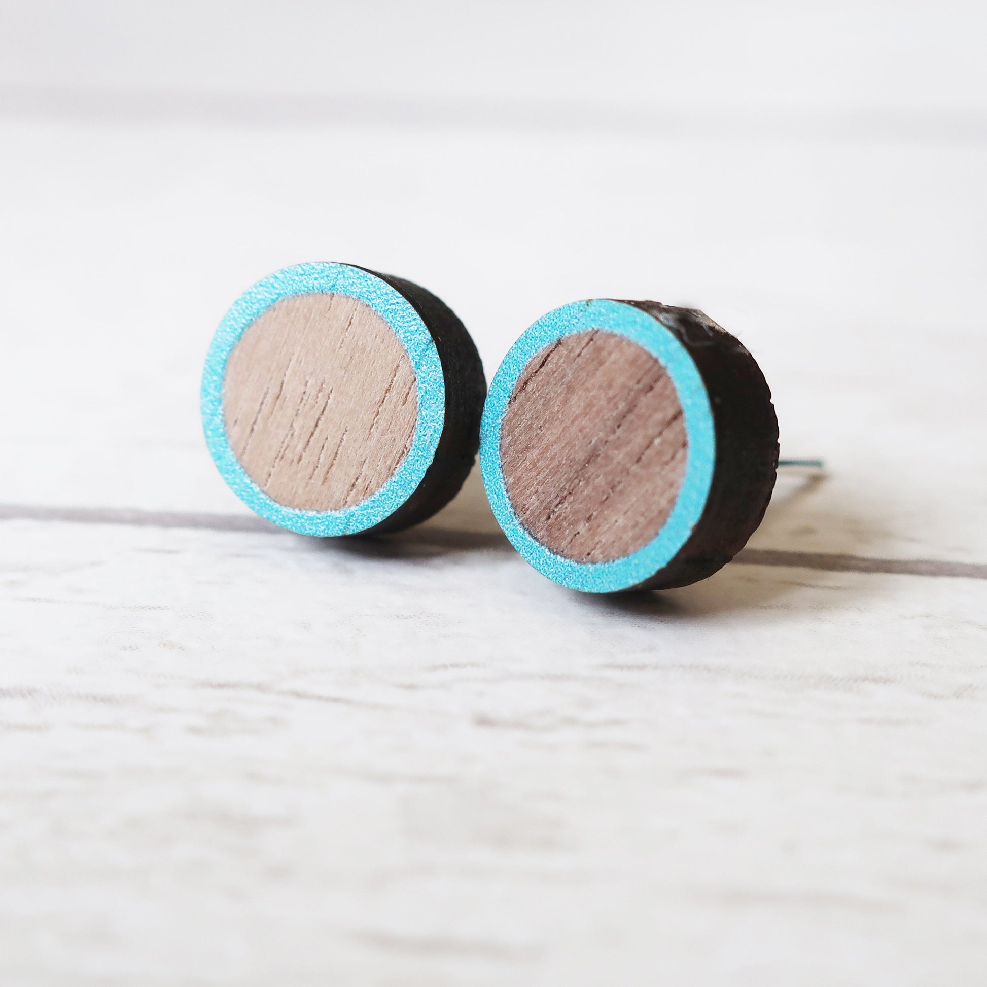 Round wooden earrings with turquoise rim on a light gray background