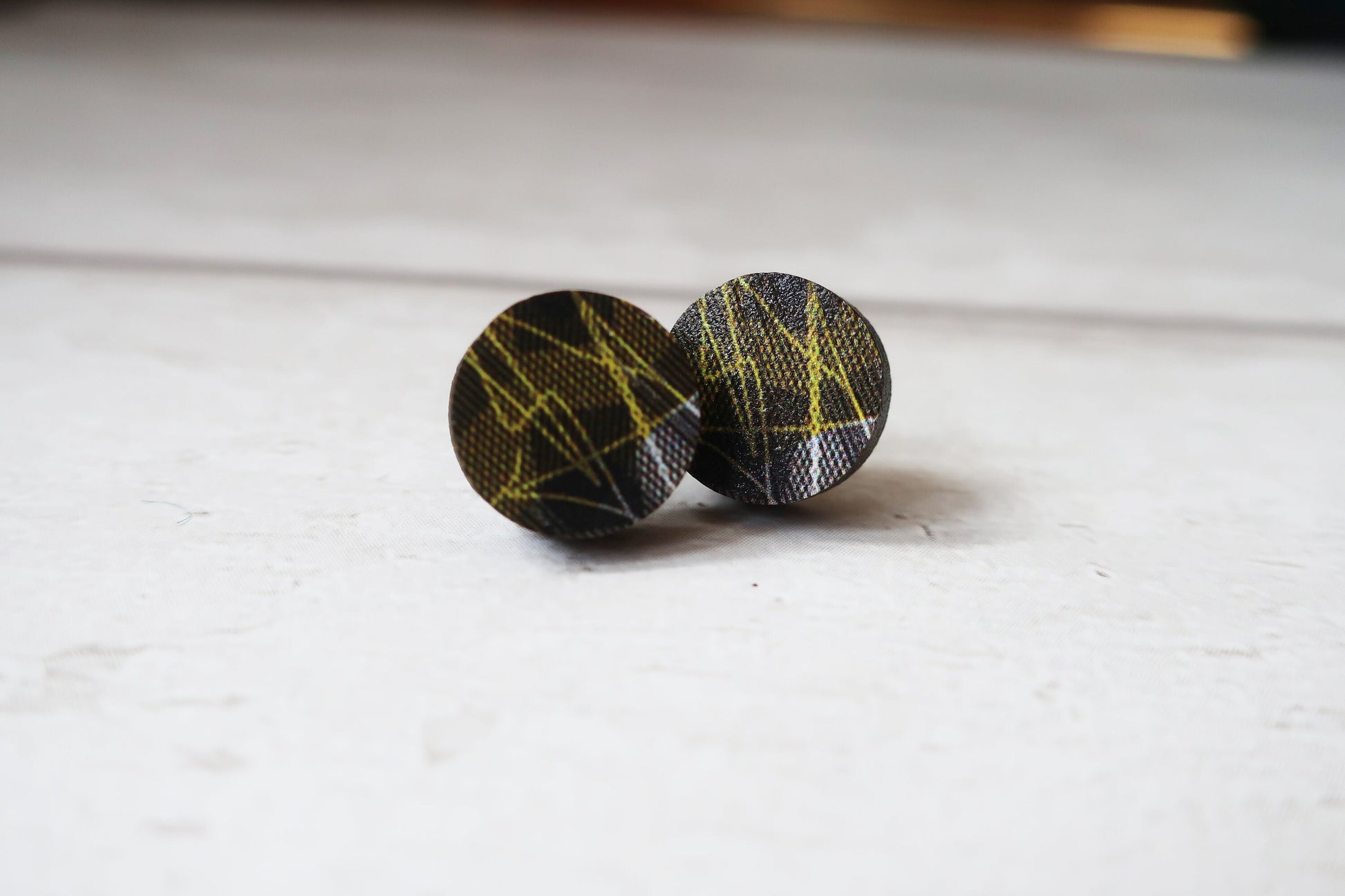 Round earrings with black and yellow pattern on a white surface
