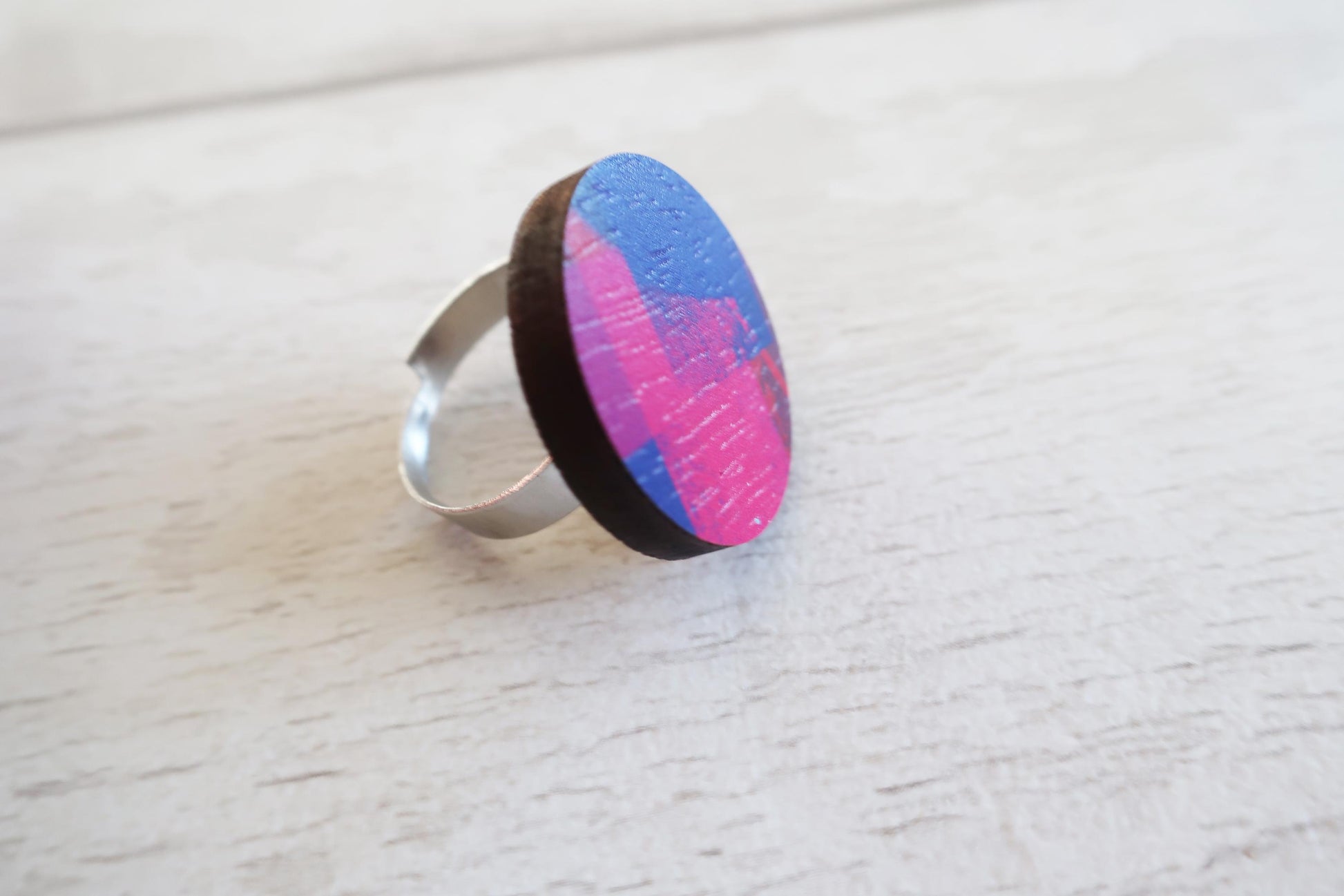 Ring with a colorful circular design on a light wooden surface