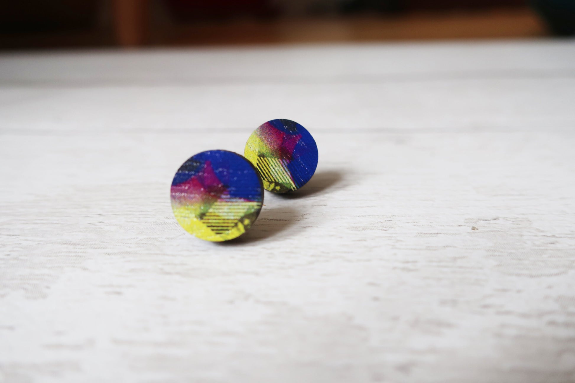 Colorful round earrings on a light wooden surface