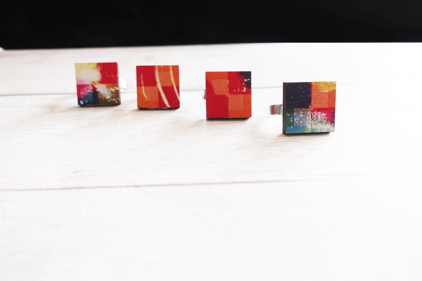Four colorful square rings on a white surface with a black background