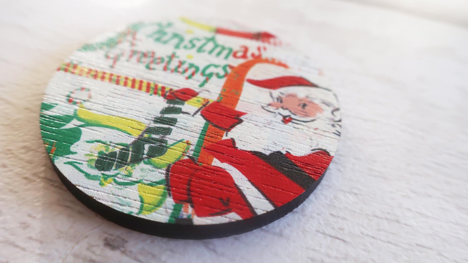 Round Christmas badge with Santa Claus design on a white surface