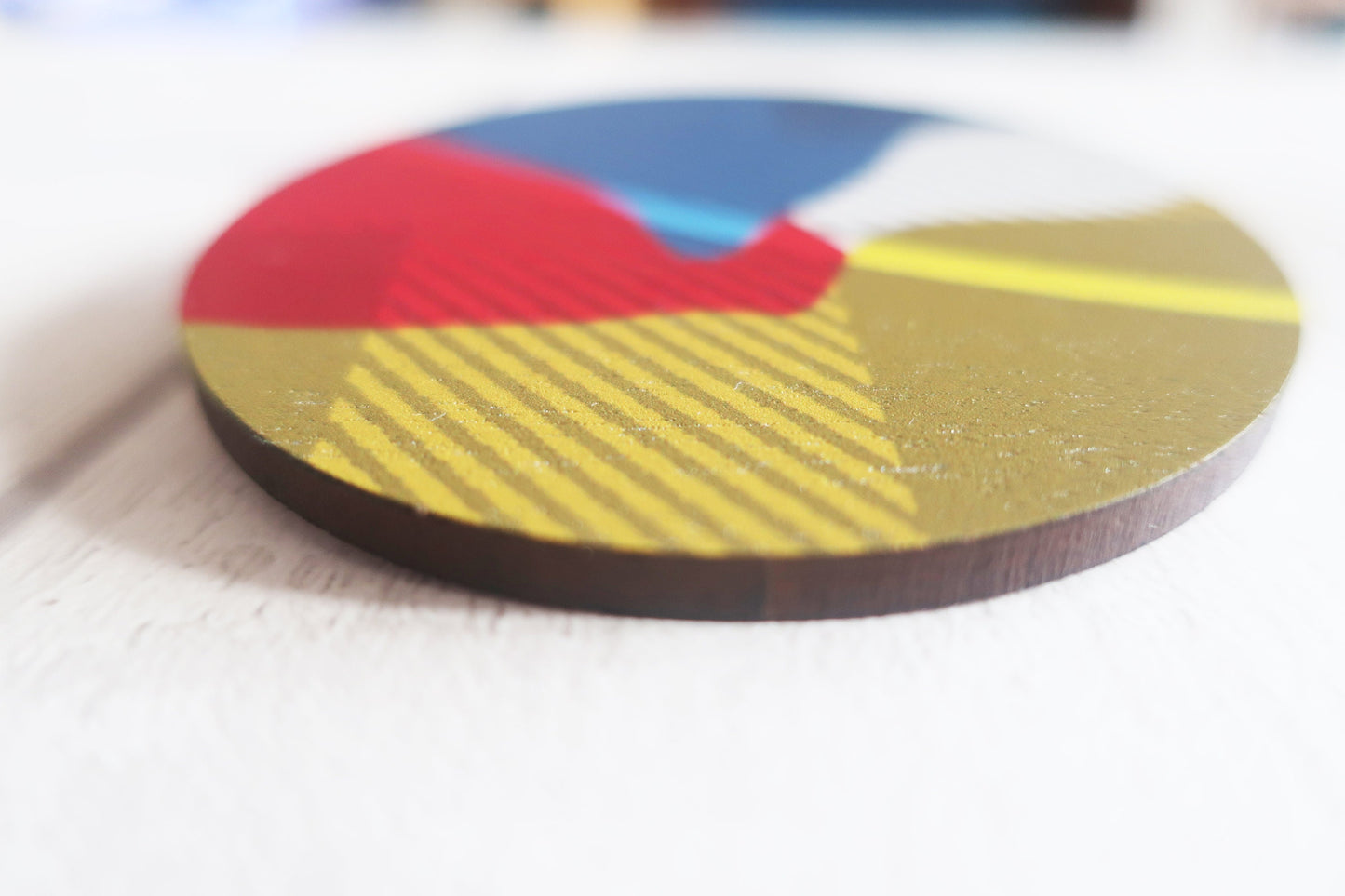 Colorful circular brooch with red, blue, and yellow sections on a white surface