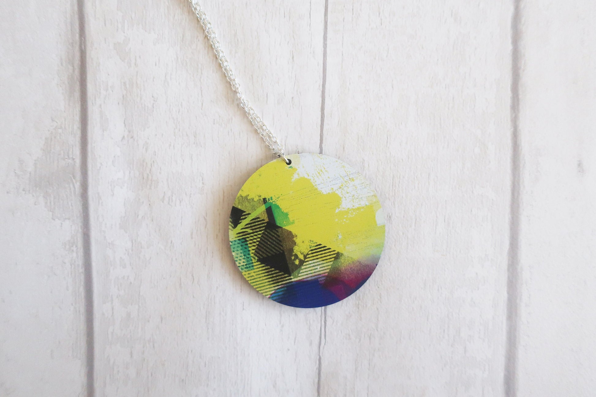 Colorful circular pendant on a white wooden background