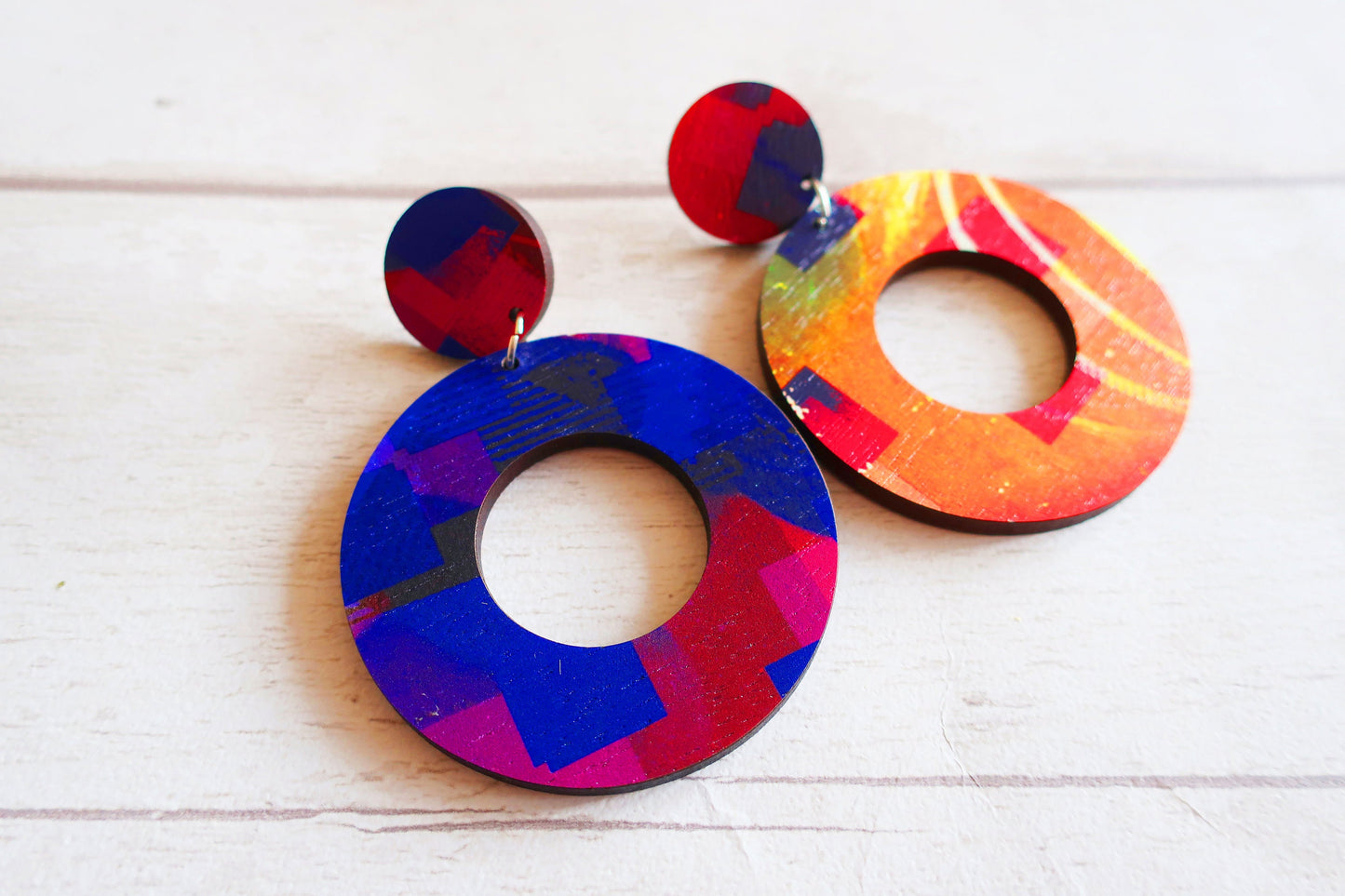 Colorful round earrings on a white wooden surface