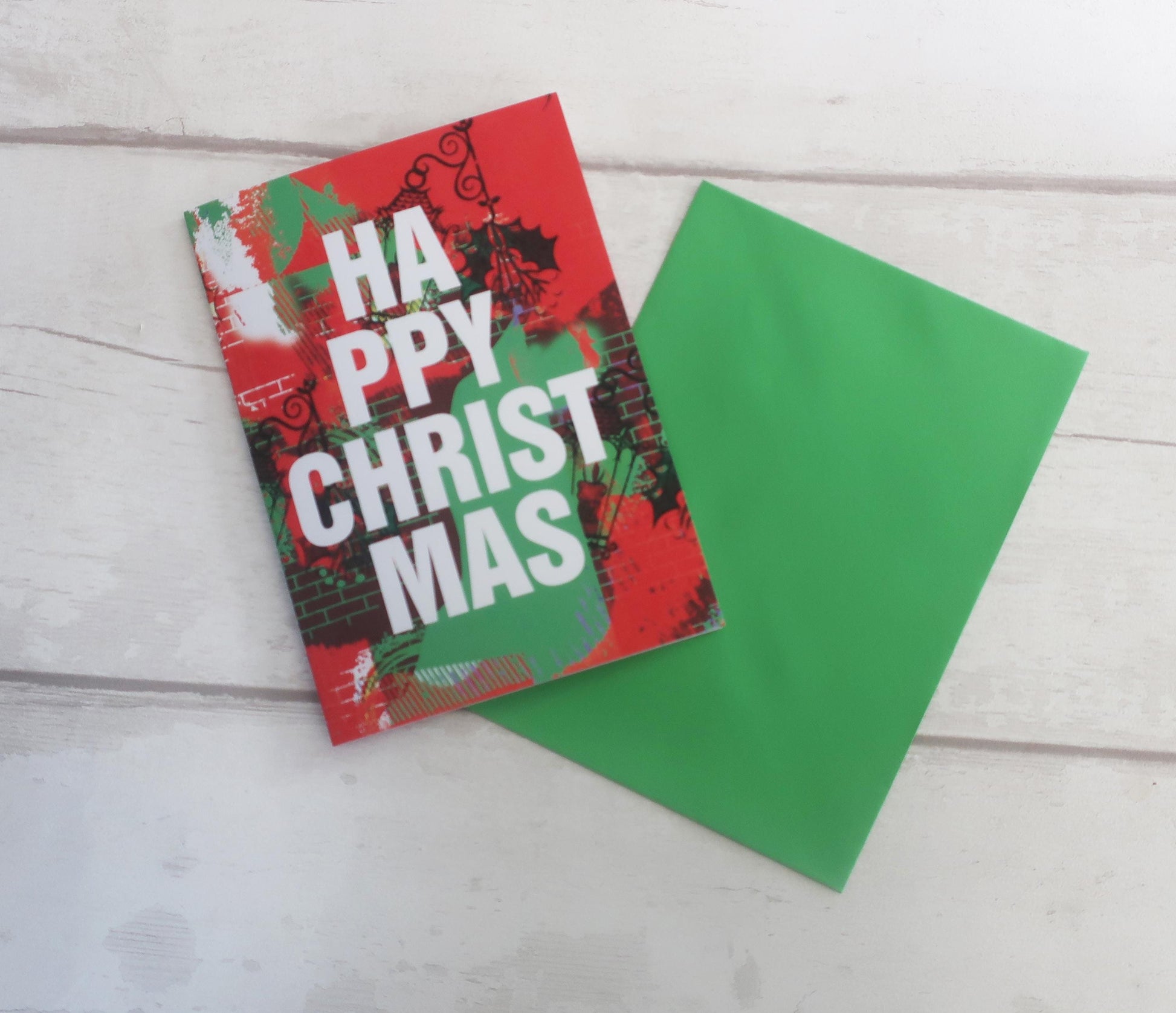 Red Christmas card with 'Happy Christmas' text on a white wooden surface