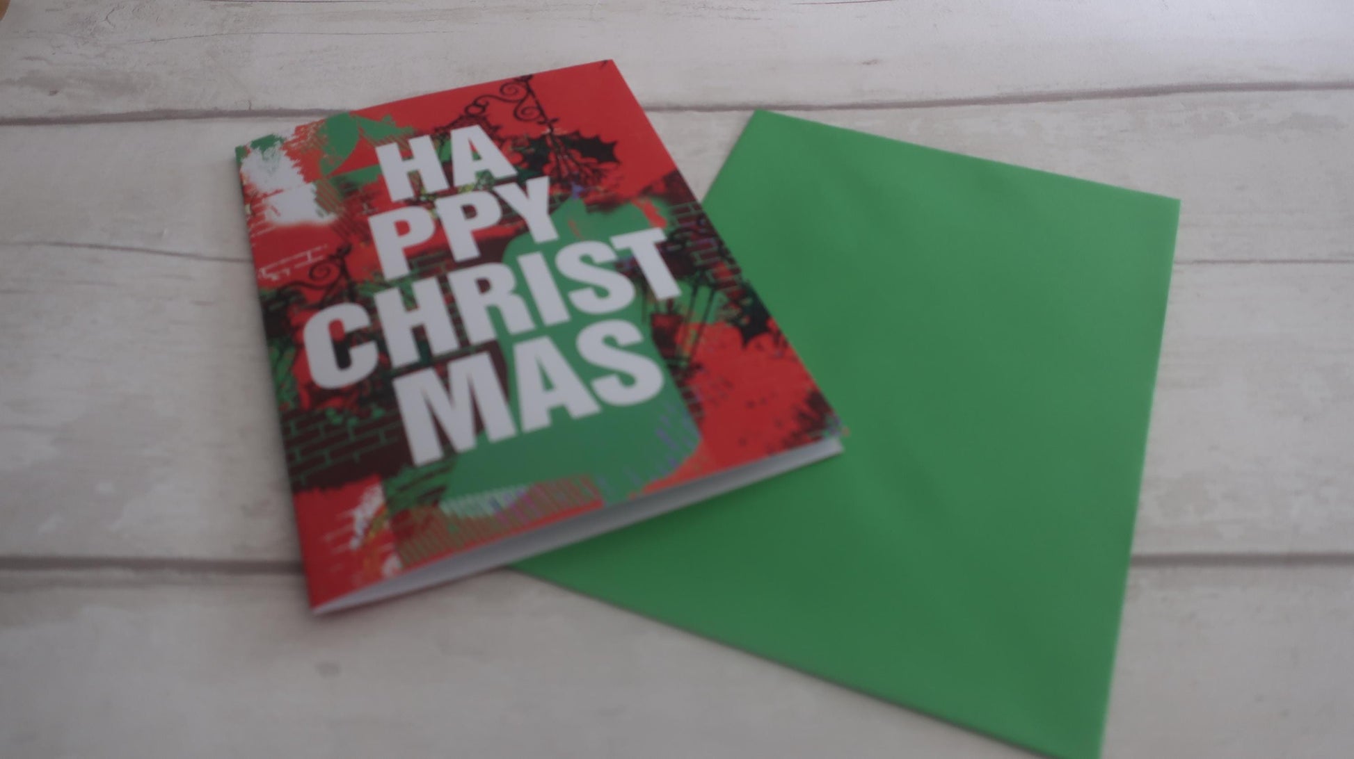 Christmas-themed card and green envelope on a wooden surface